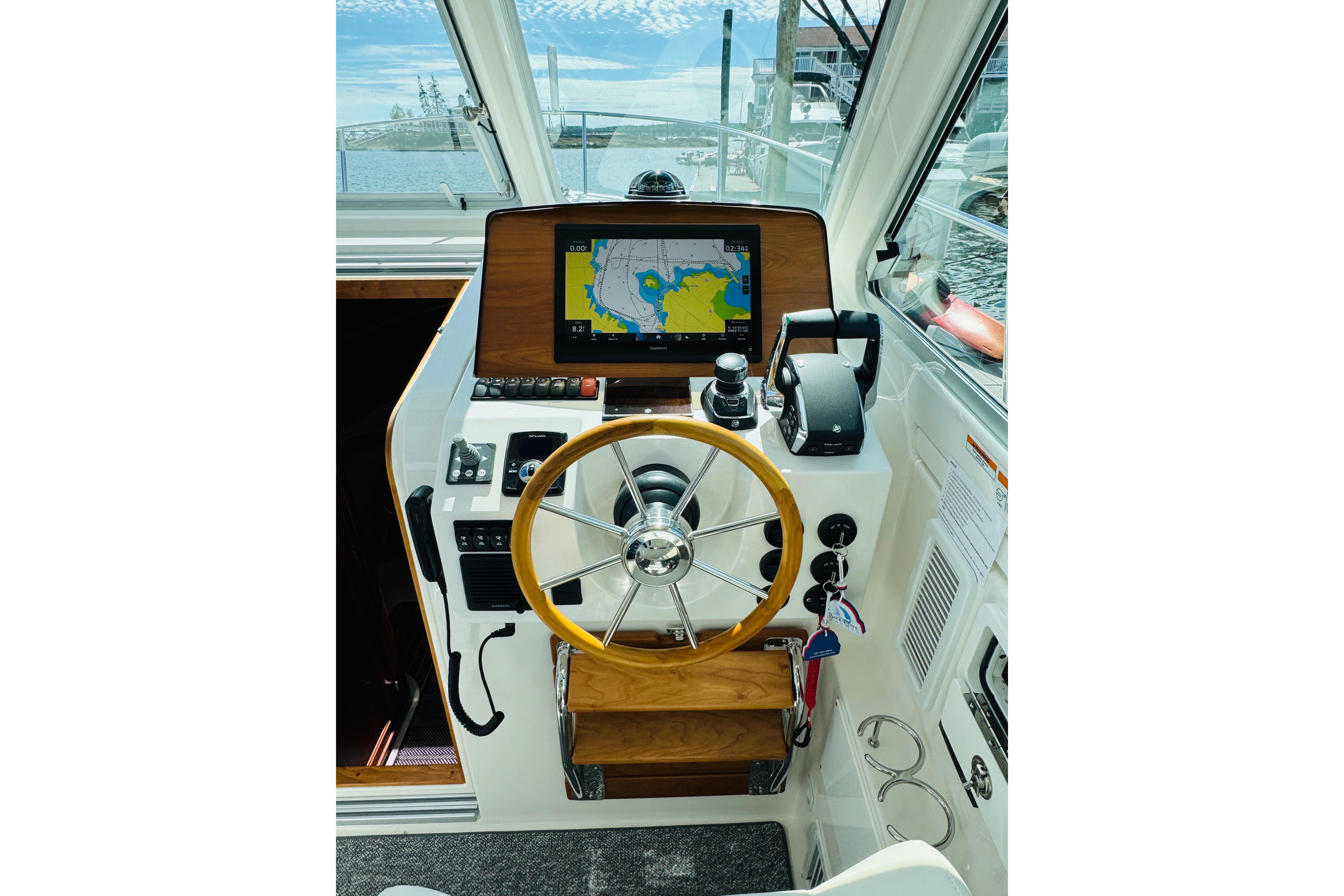 Helm of 2025 Back Cove 34O boat with navigation screen and steering wheel.