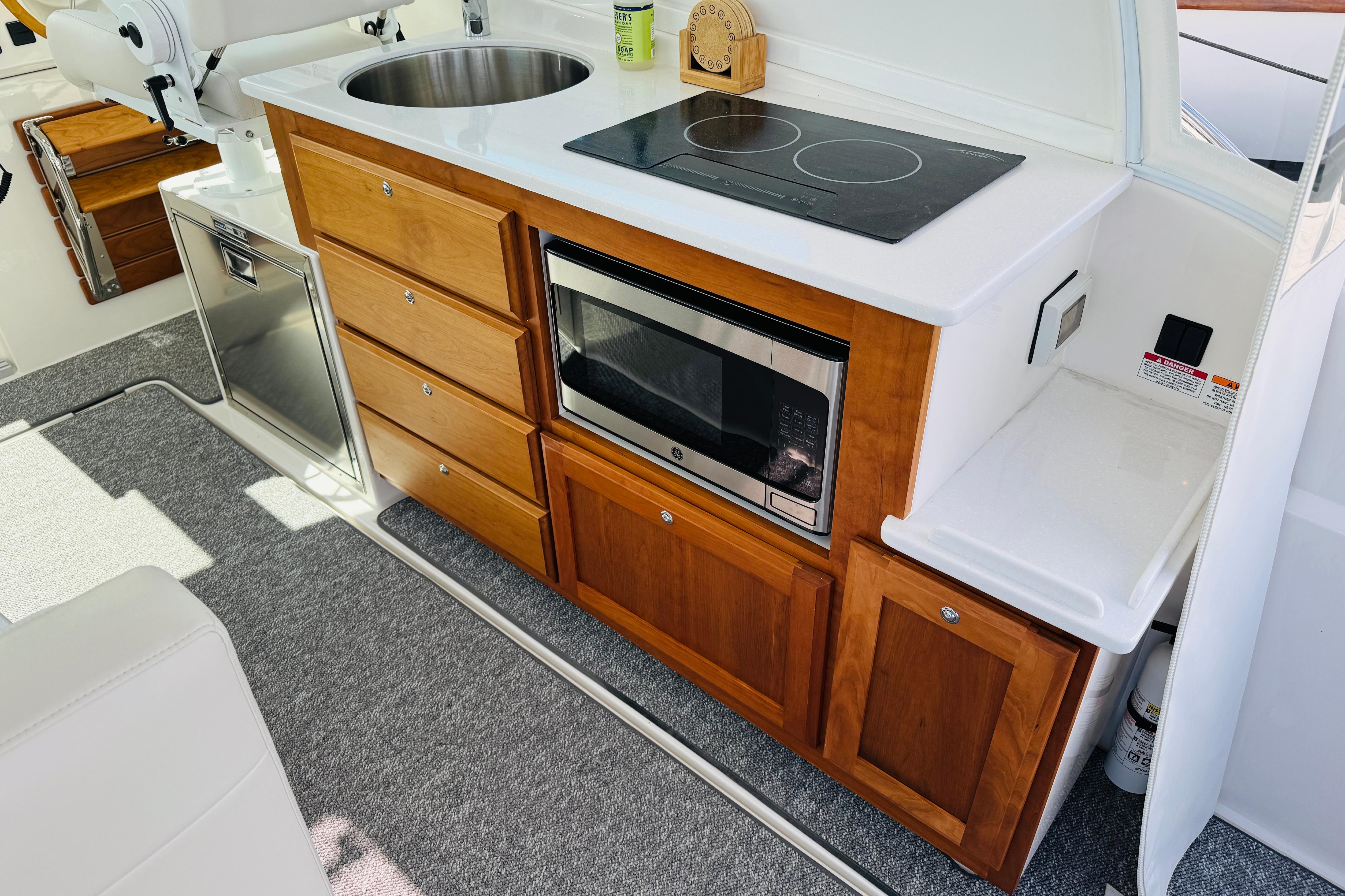 Modern galley kitchen in 2025 Back Cove 34O boat with stove, sink, and microwave.