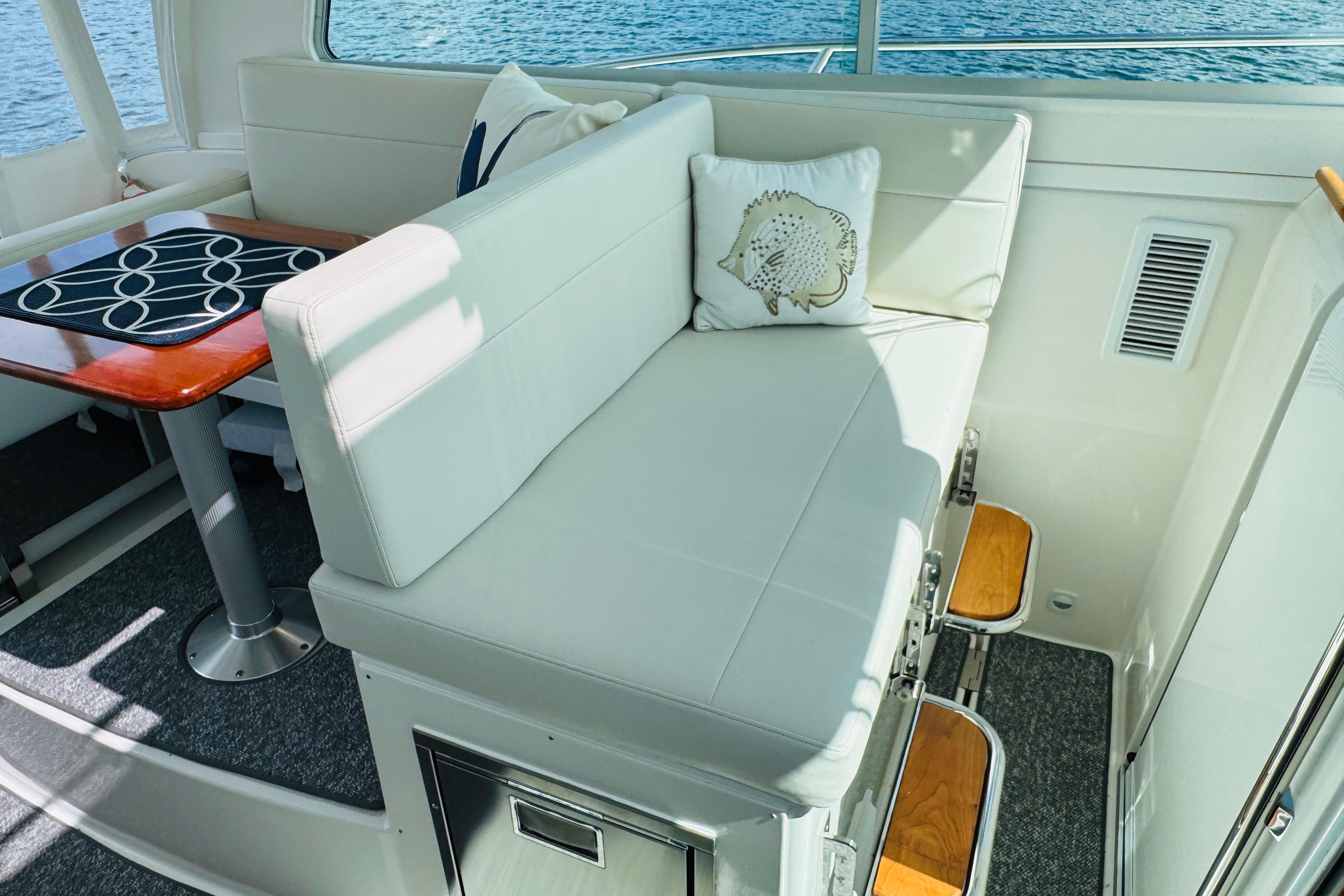 Luxurious interior of 2025 Back Cove 34O yacht with white seating and wooden accents.