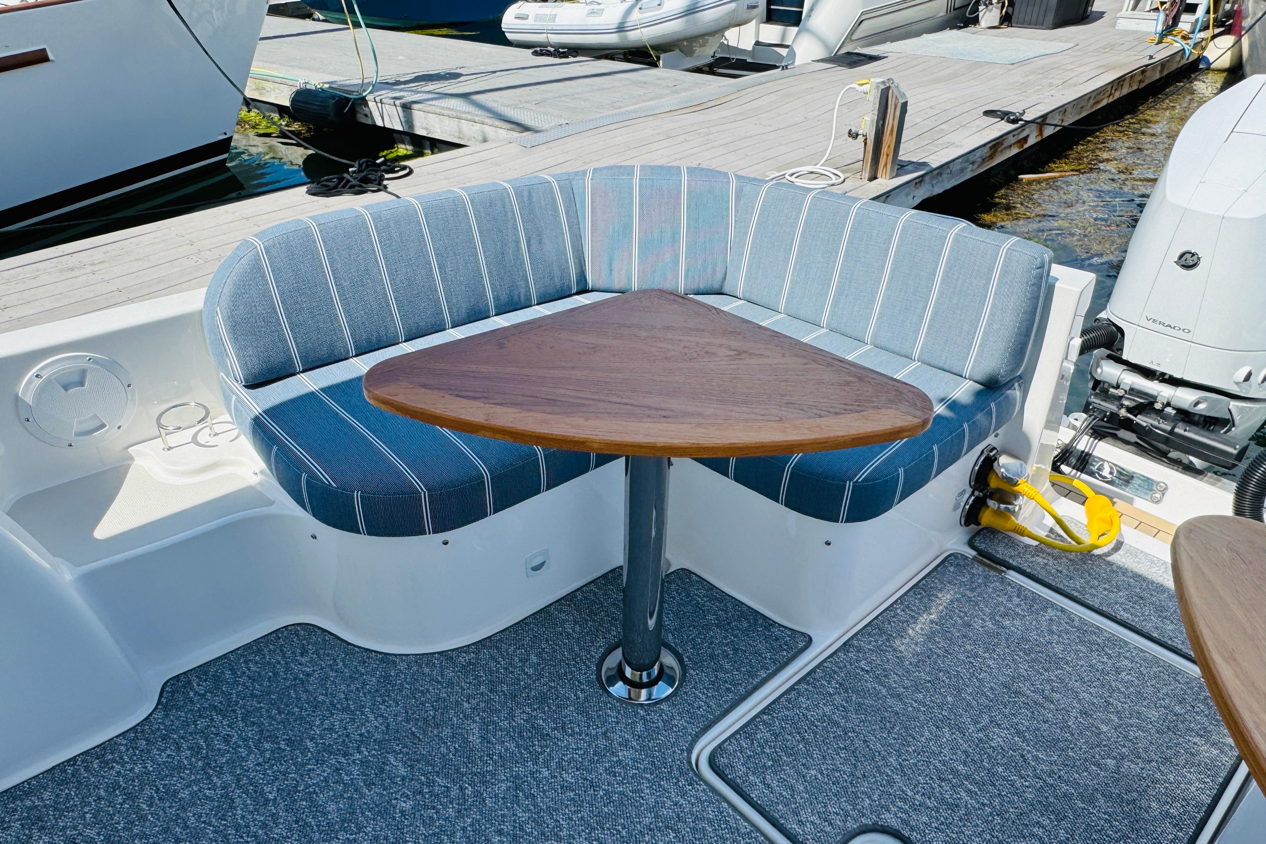 Cozy seating area on 2025 Back Cove 34O boat with striped cushions and triangular table.
