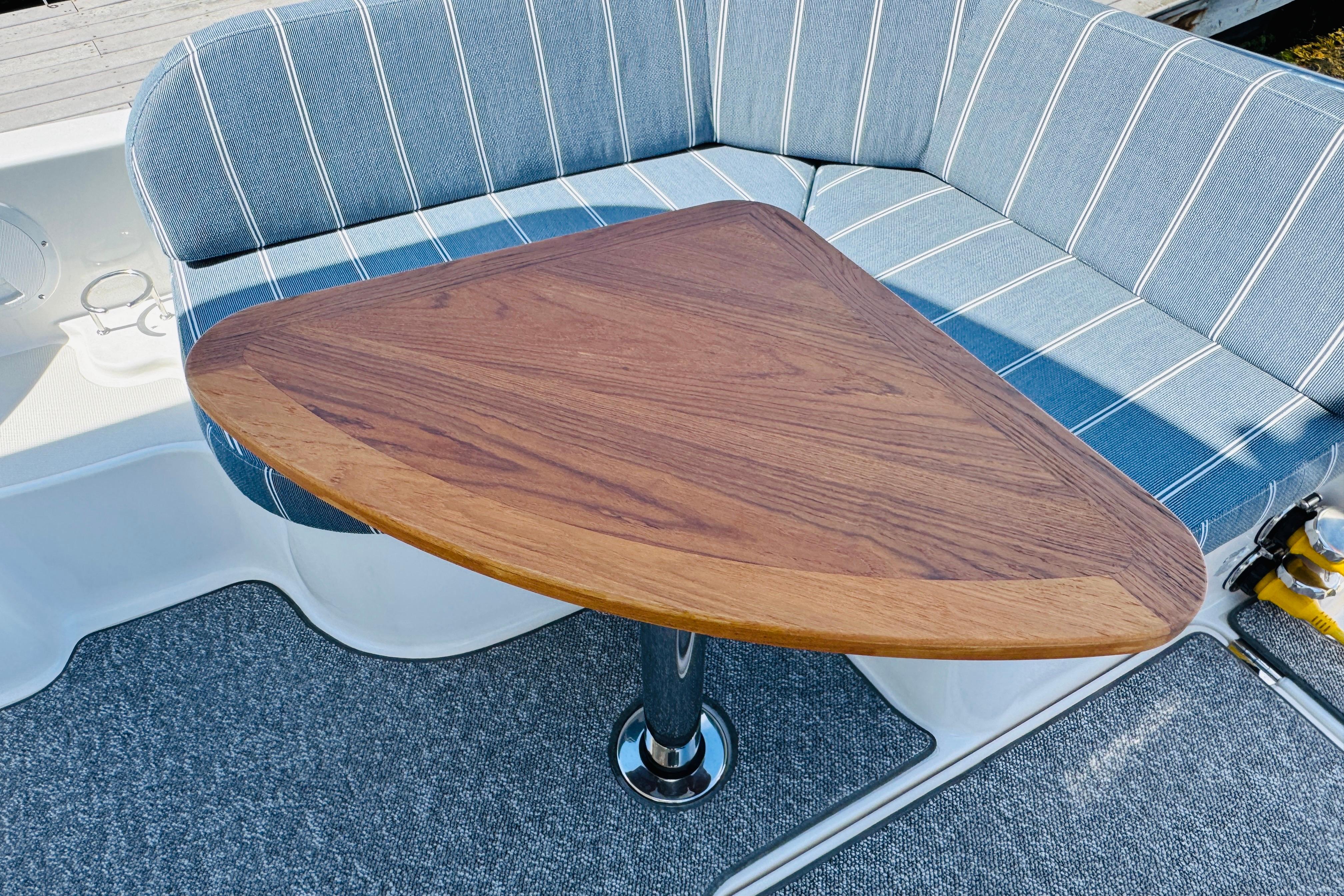 2025 Back Cove 34O boat interior with triangular wooden table and striped seating.
