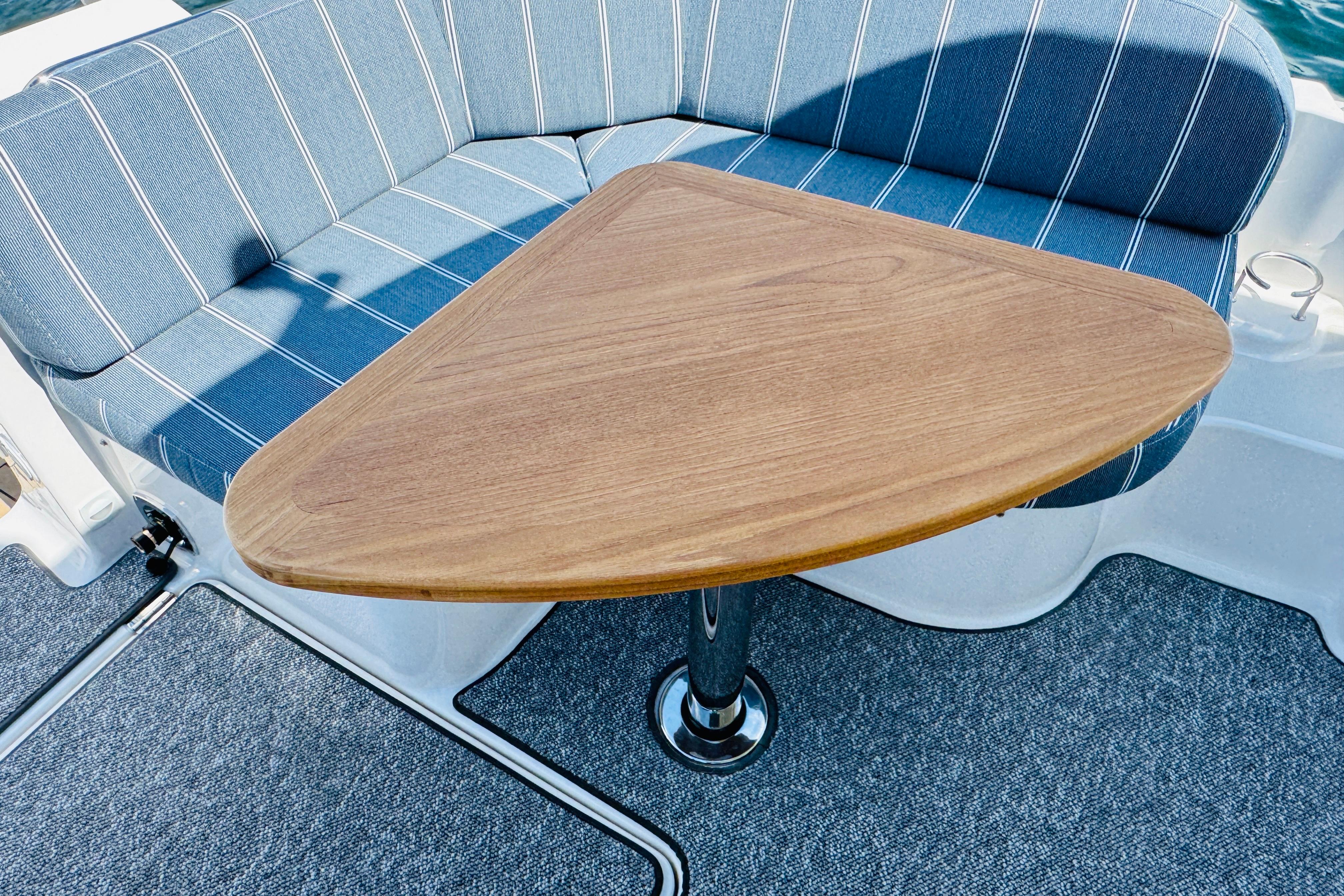 Back Cove 34O 2025 boat interior with triangular wooden table and striped seating.