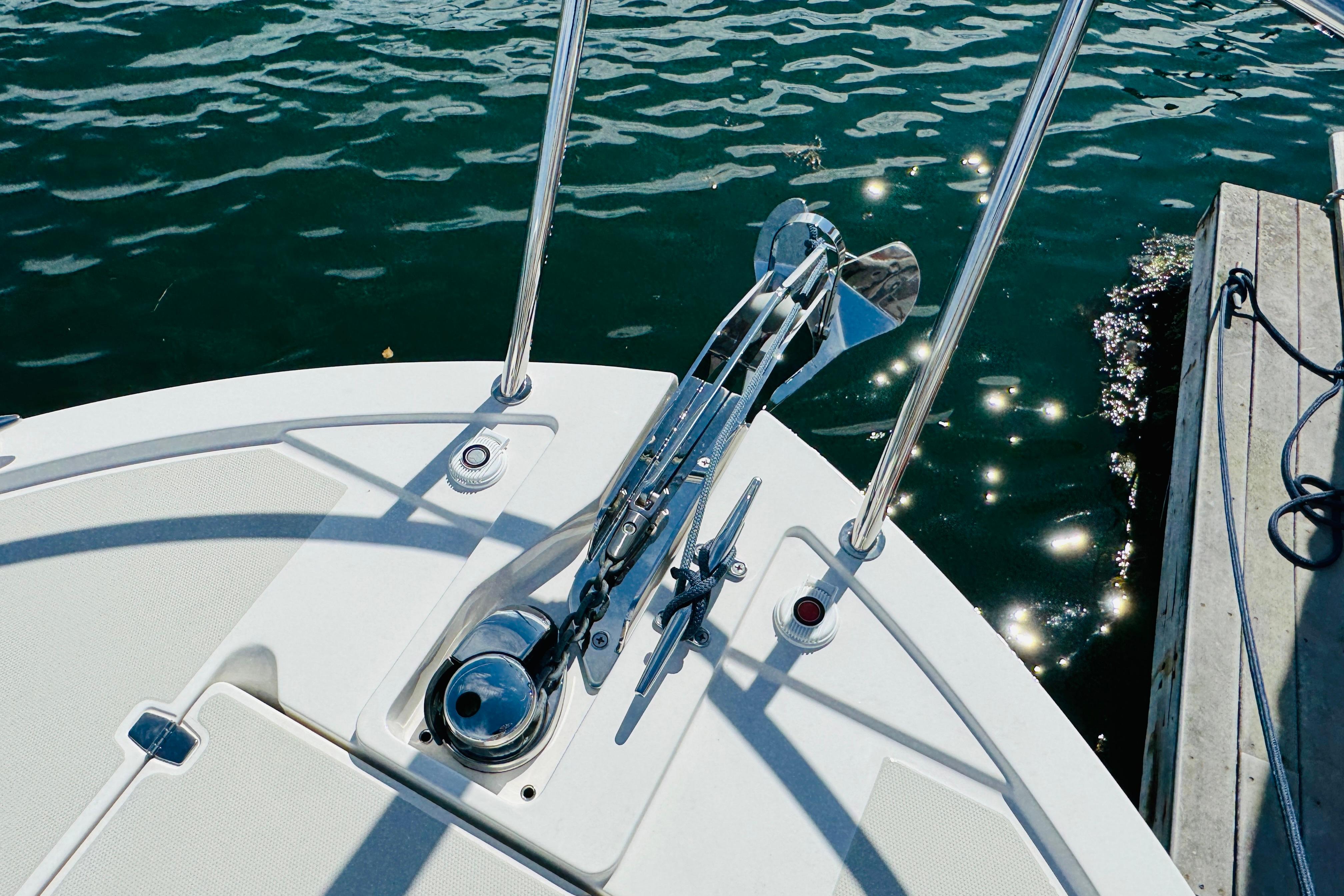 Bow of 2025 Back Cove 34O boat with anchor, docked on sparkling water.