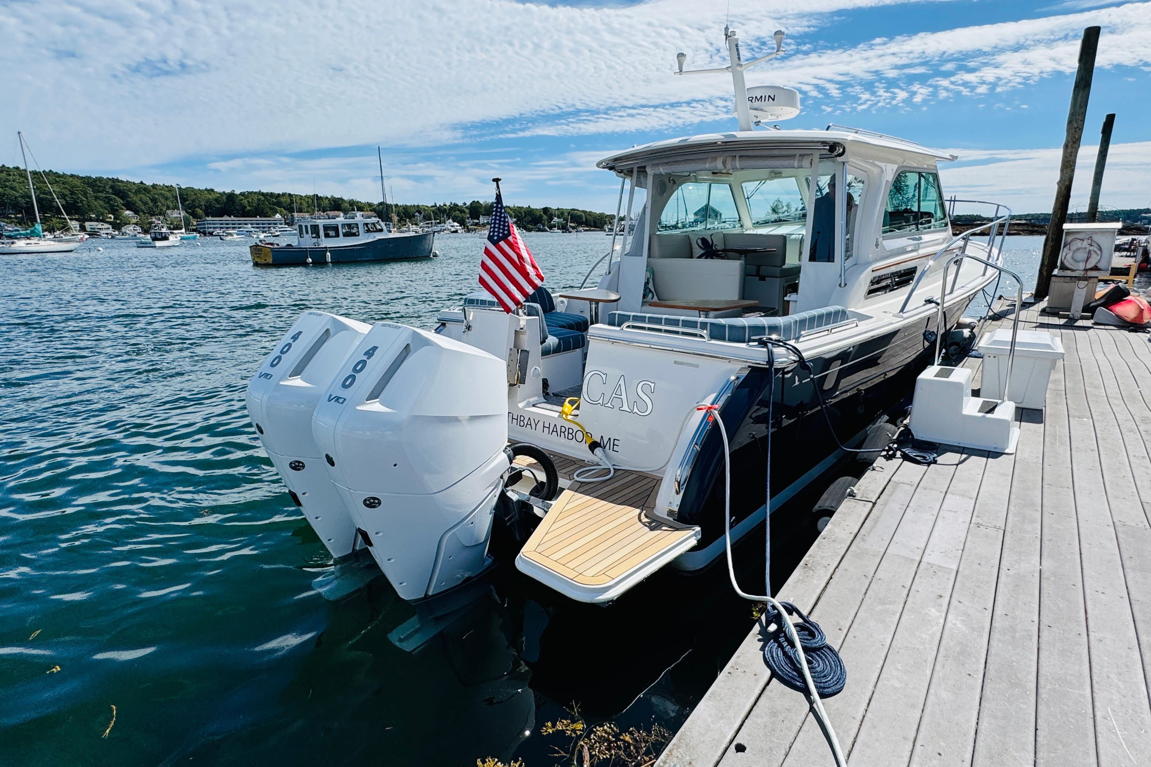 2025 Back Cove 34O boat docked, featuring dual outboard engines and American flag.