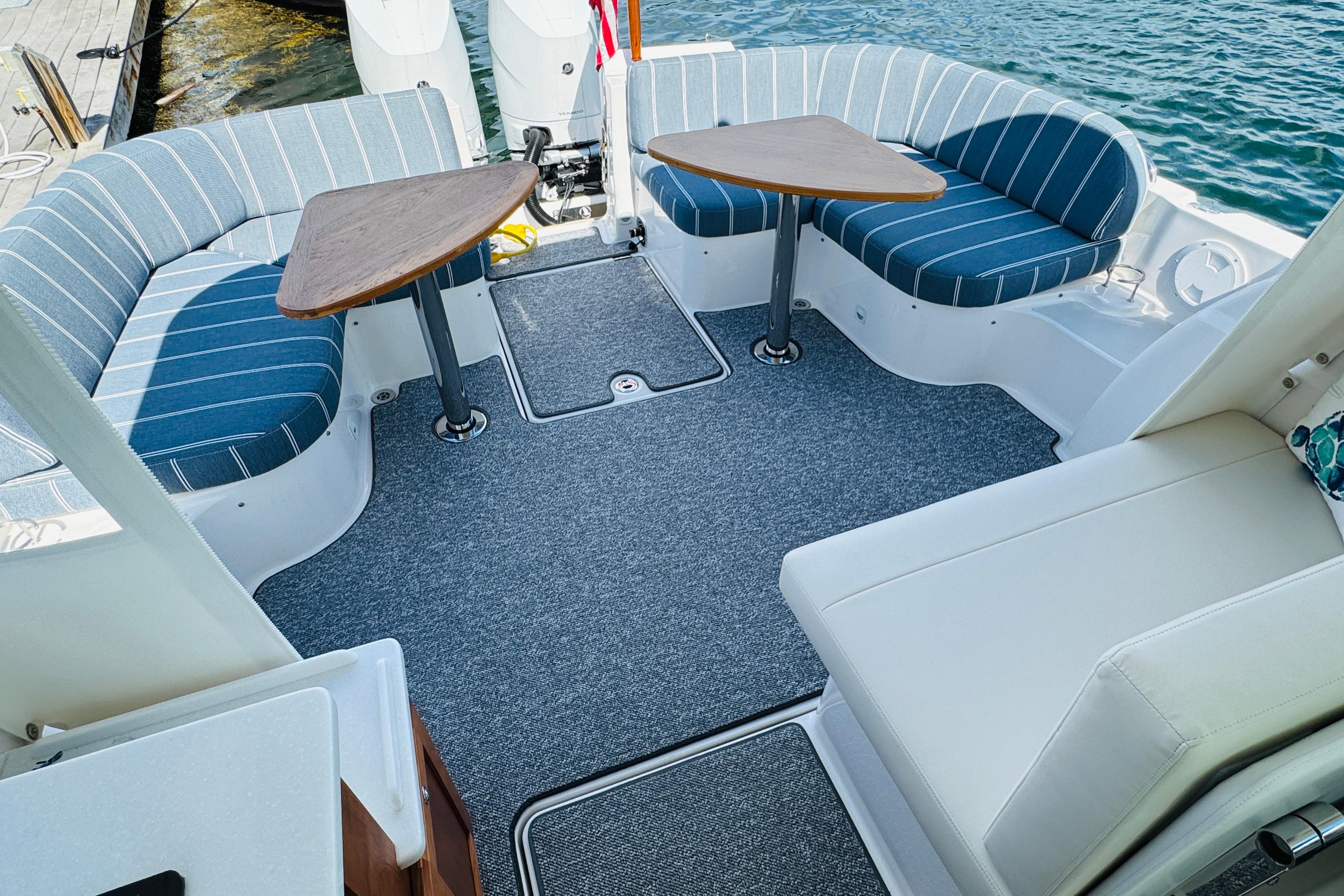 2025 Back Cove 34O boat interior with striped seating and dual tables on a sunny day.