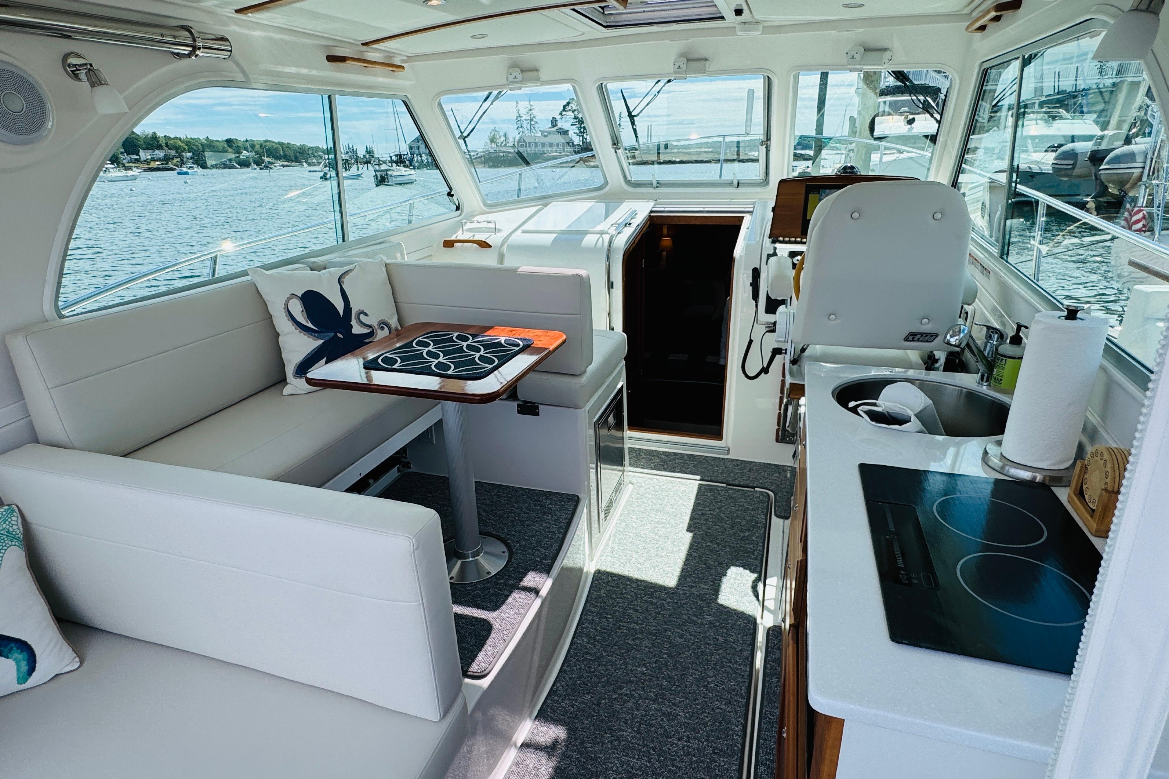 Interior of 2025 Back Cove 34O yacht with seating, table, and kitchenette.