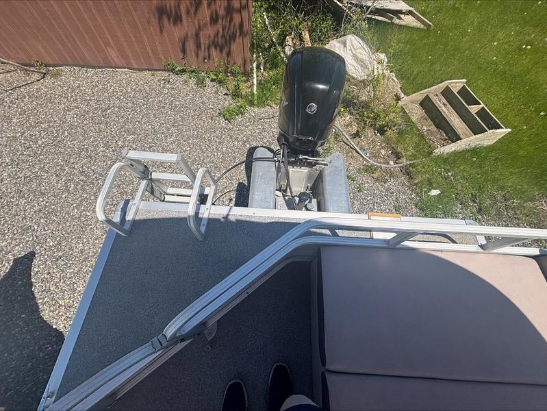 2015 Sun Tracker PARTY BARGE® 22 DLX with outboard motor, parked on gravel.