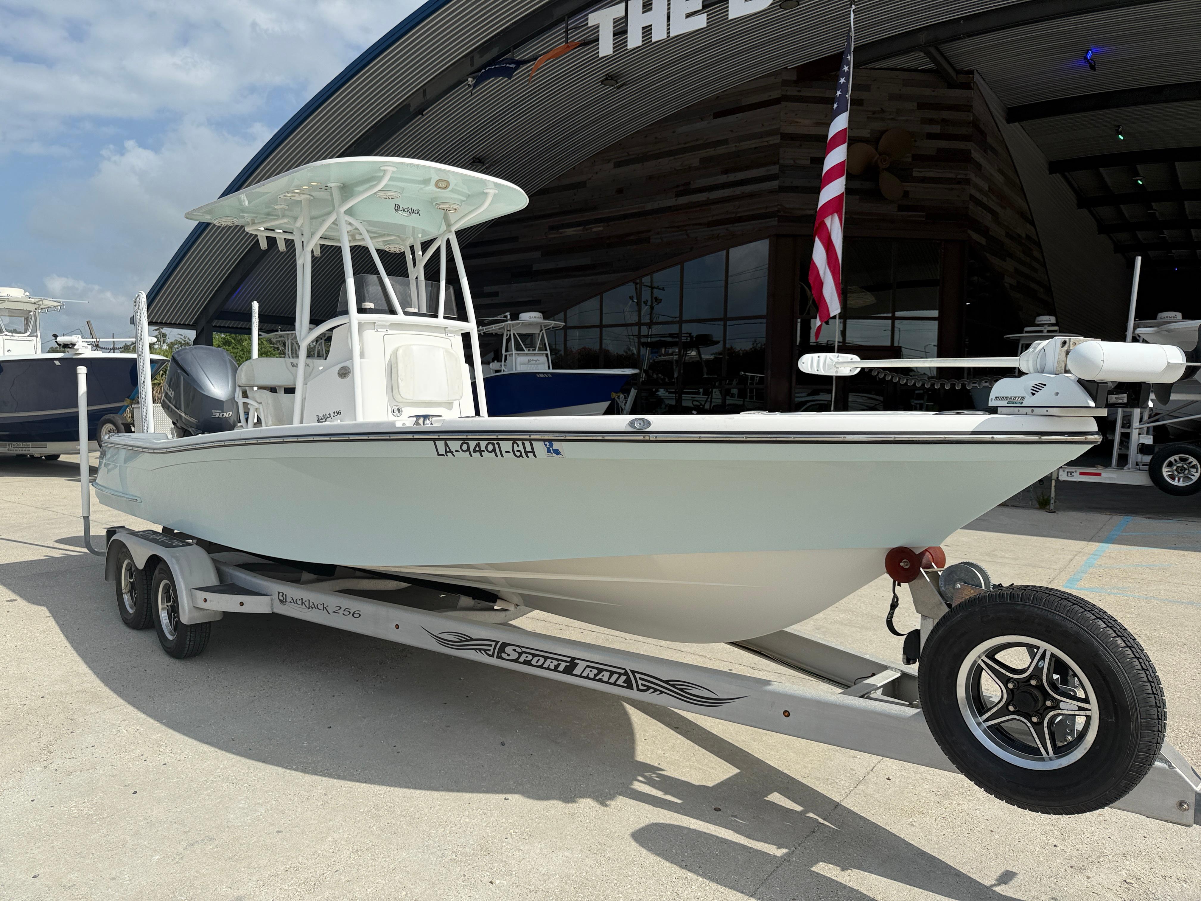 2018 BlackJack 256 boat on trailer, parked outside a dealership with an American flag.