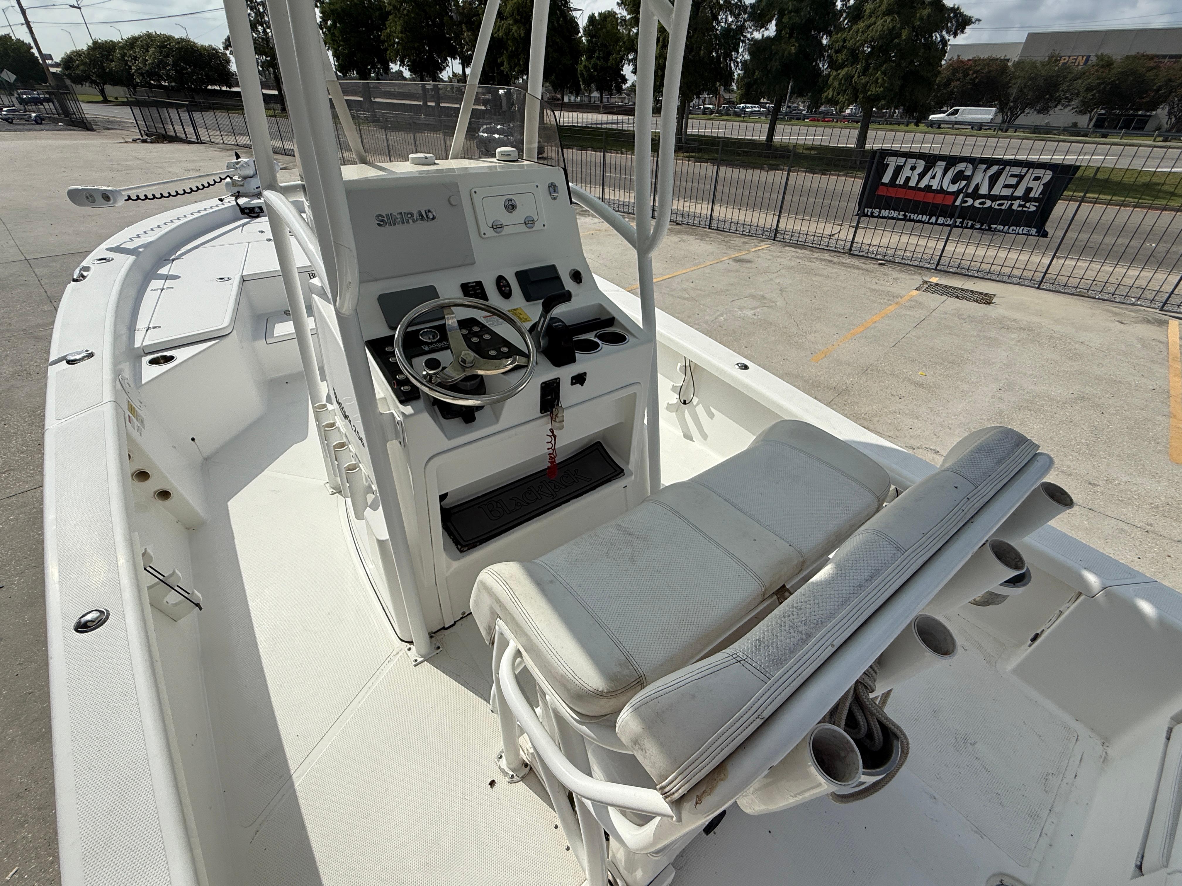 2018 BlackJack 256 boat interior with steering console and seating, parked outdoors.