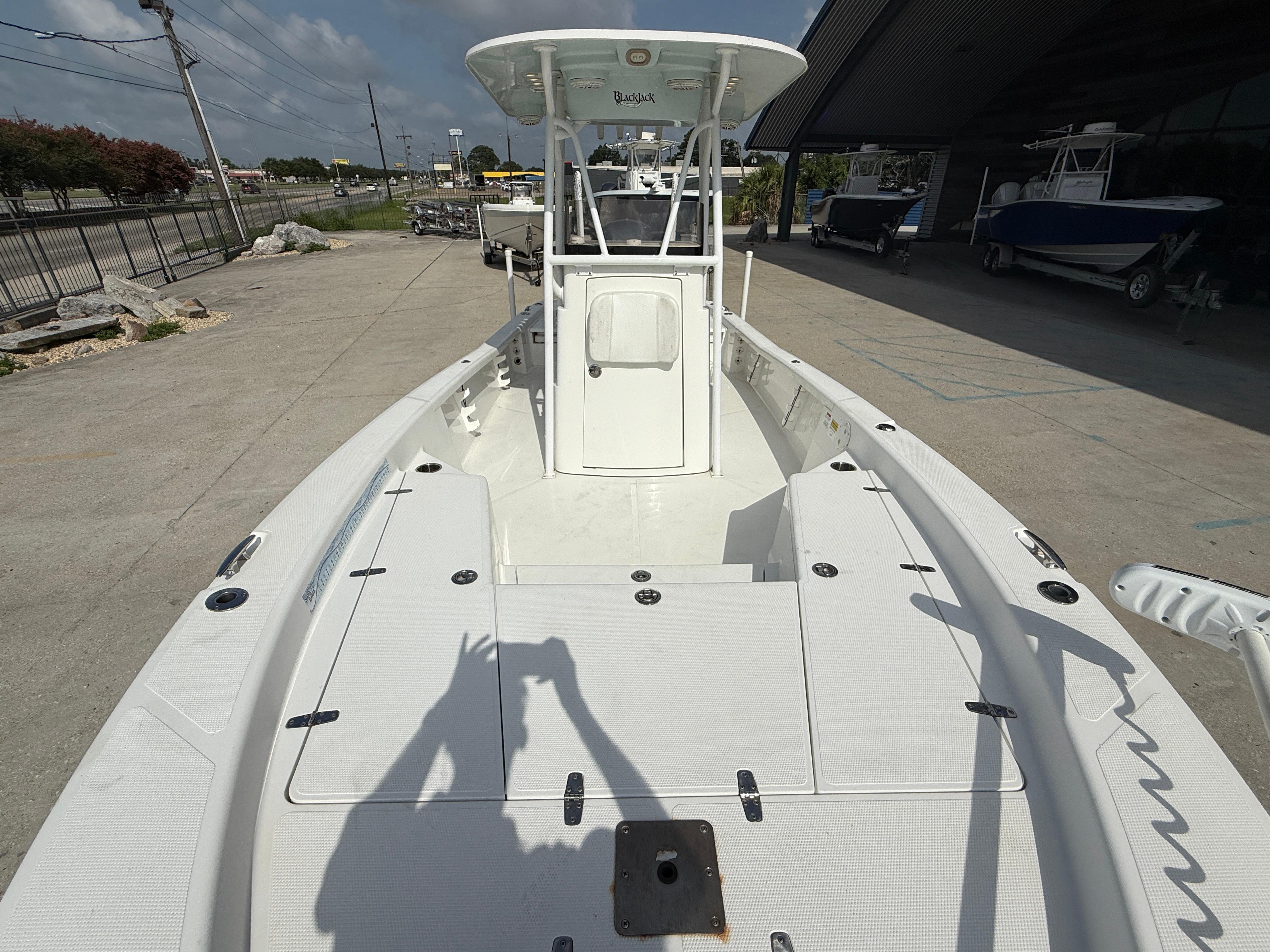 2018 BlackJack 256 boat on display at a dealership, showcasing spacious deck and console.