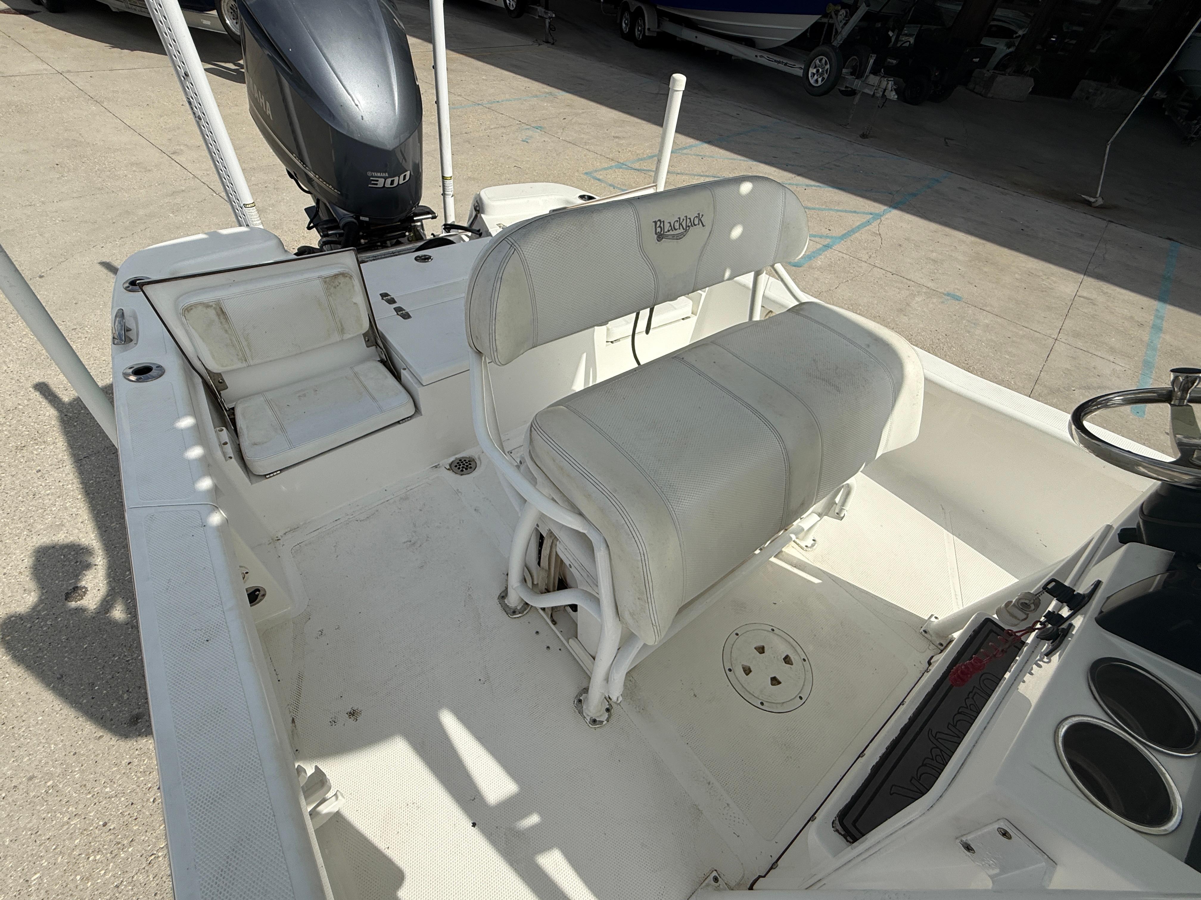 2018 BlackJack 256 boat interior with seating and engine, parked on concrete.