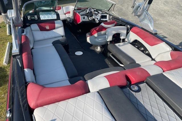 2013 MasterCraft X-25 boat interior with red and gray seating, steering wheel, and dashboard.