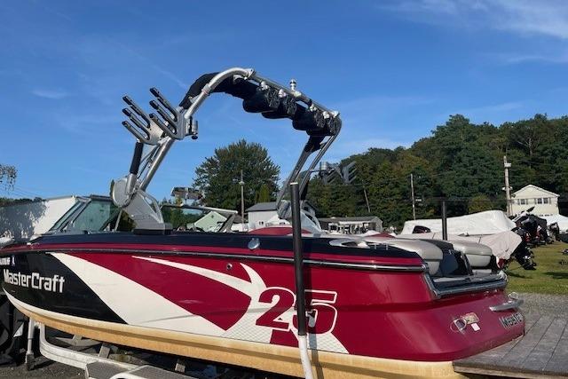 2013 MasterCraft X-25 boat with red and white design, parked outdoors.