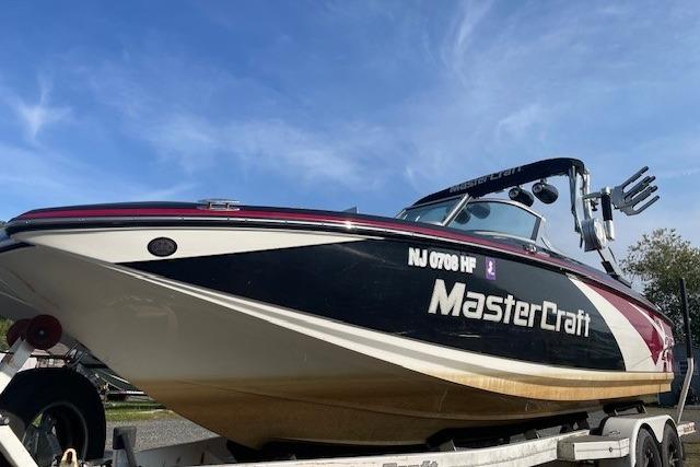 2013 MasterCraft X-25 boat on trailer under clear blue sky.
