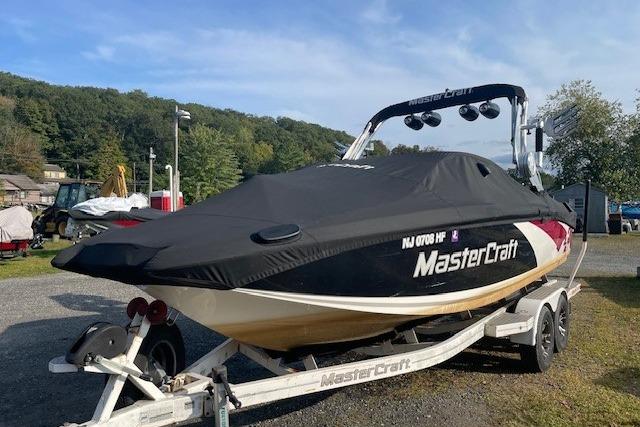 2013 MasterCraft X-25 boat on trailer with cover, parked outdoors.