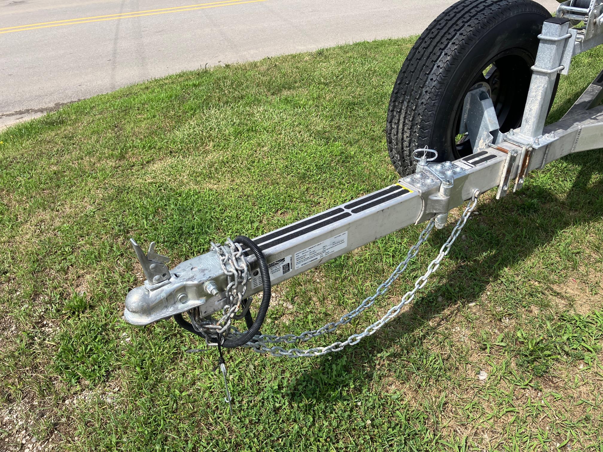 Trailer hitch of 2017 Pro-Drive SBX Series 18' on grass, showing chains and wheel.