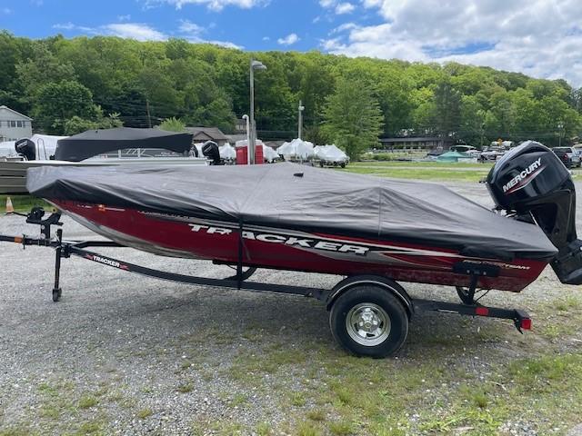 2023 Tracker Pro Team 175 TXW boat covered, on trailer, outdoors with trees in background.