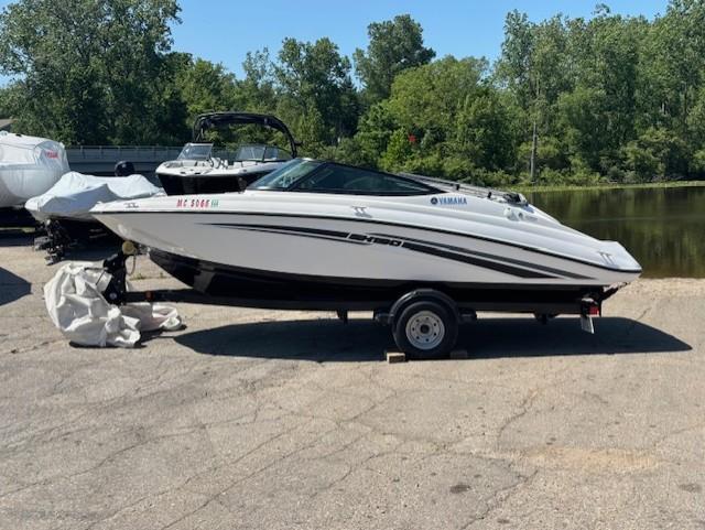 2017 Yamaha SX190 boat on trailer, parked near a lake with trees in the background.