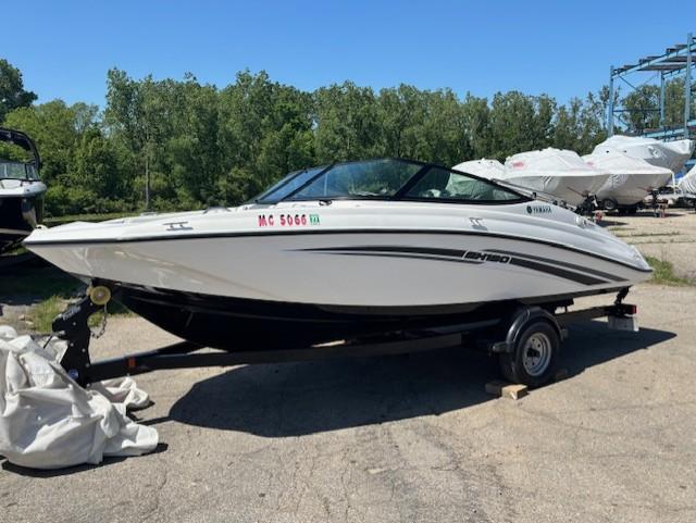 2017 Yamaha SX190 boat on trailer, parked outdoors, surrounded by trees and other boats.