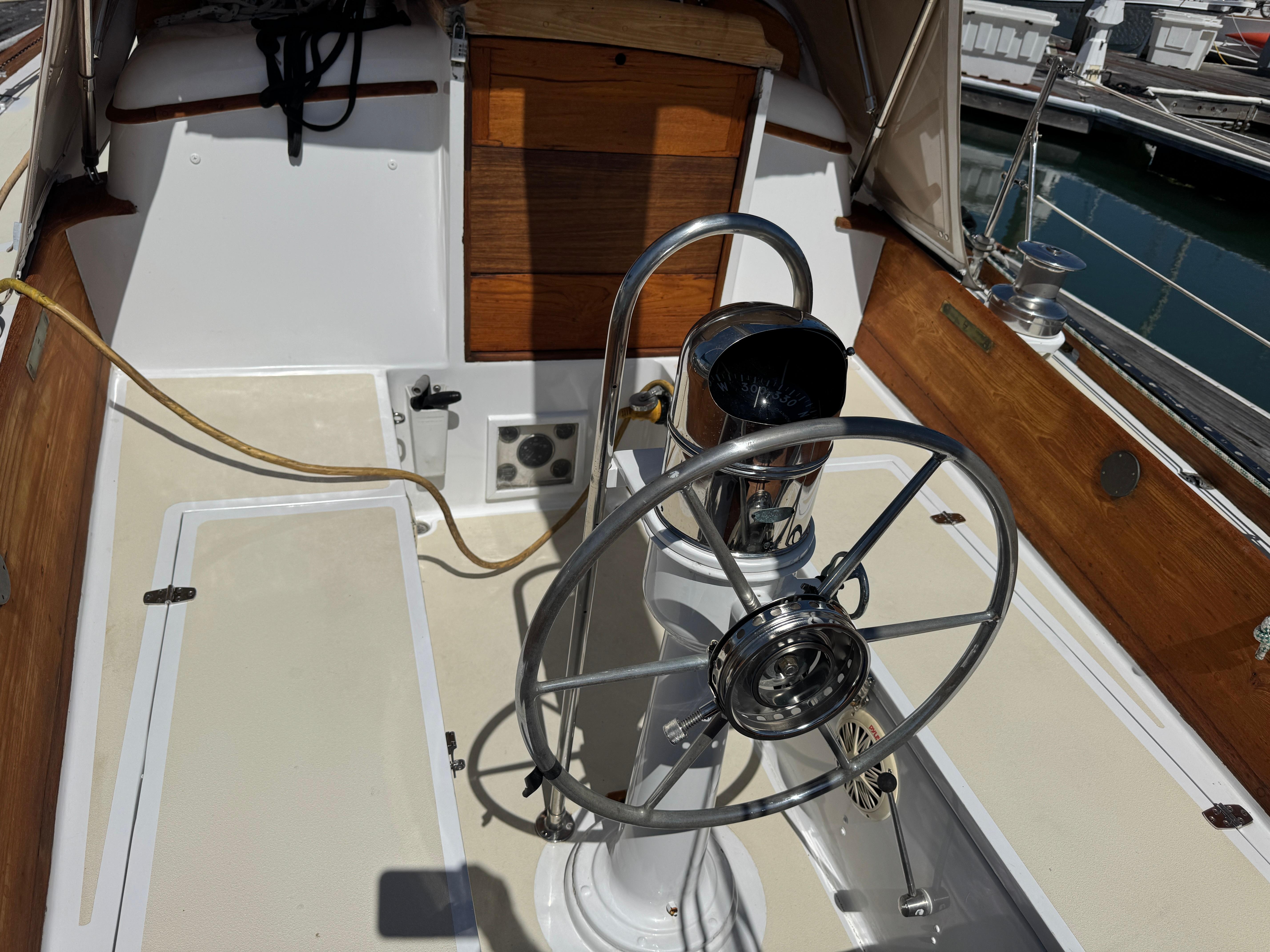 Cockpit of a 1970 Cheoy Lee Luders 36 sailboat with a metal steering wheel.