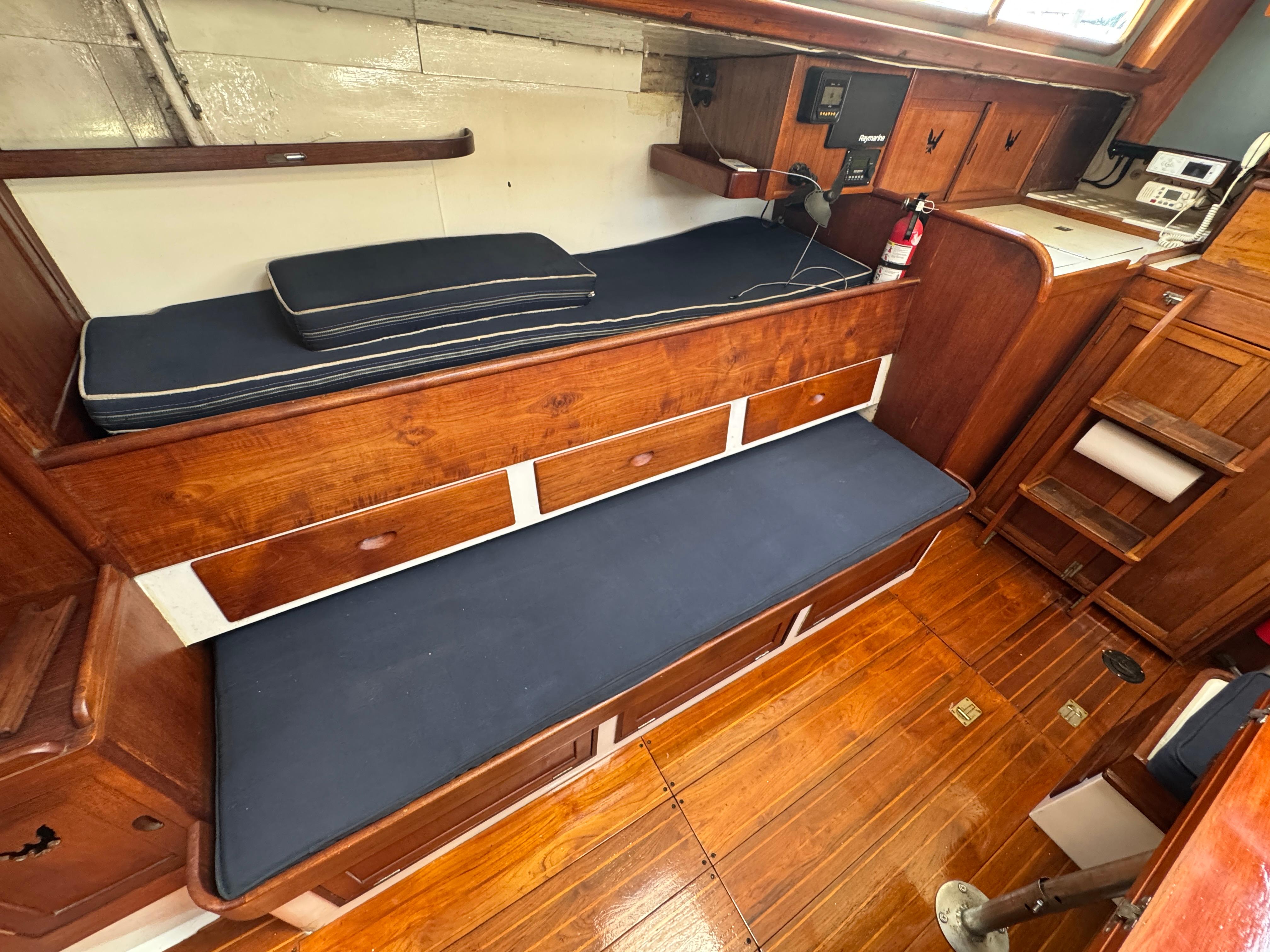 Interior of 1970 Cheoy Lee Luders 36 sailboat with wooden cabinetry and blue cushions.