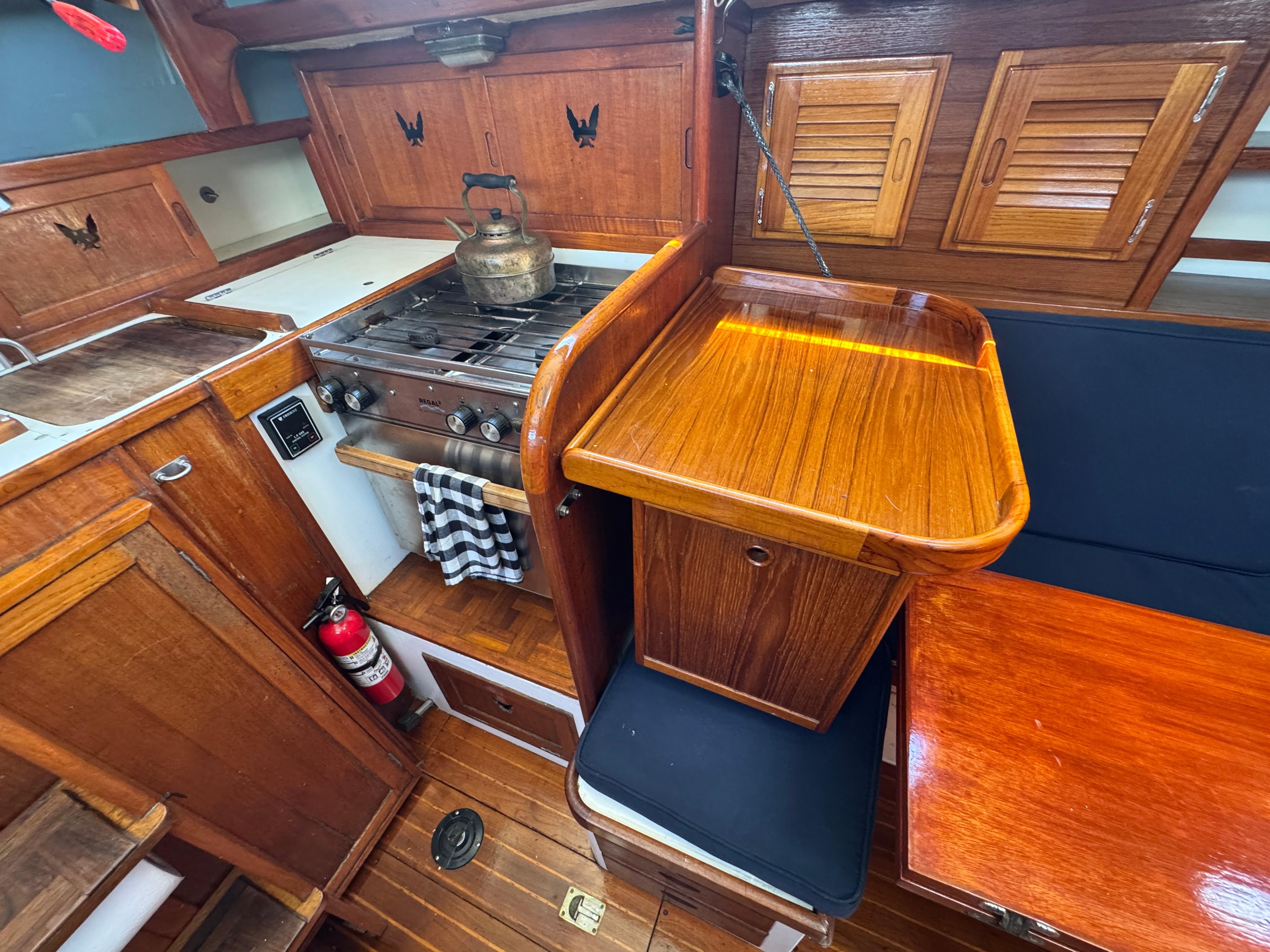 1970 Cheoy Lee Luders 36 yacht interior with wooden cabinetry and stove.