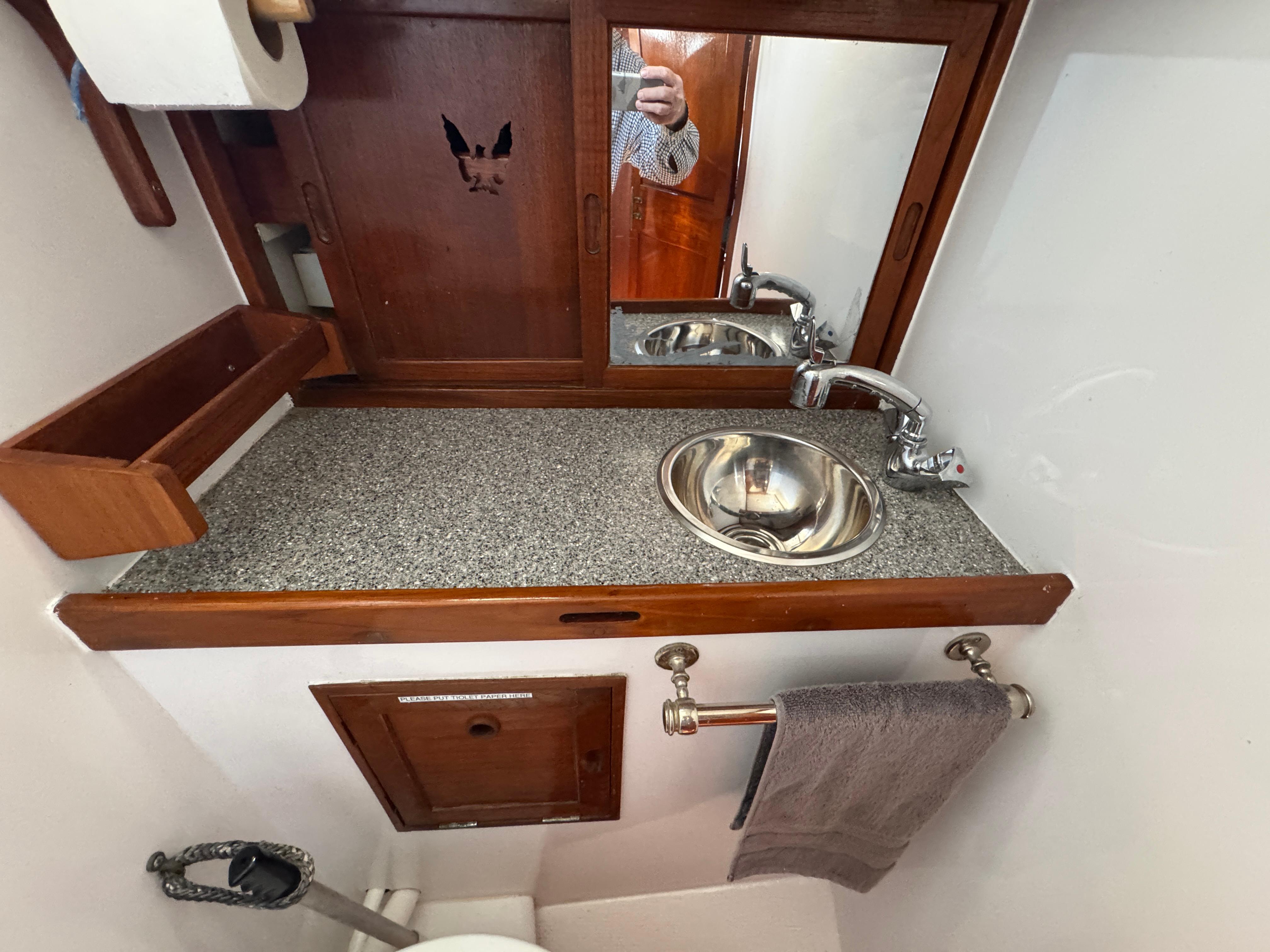 1970 Cheoy Lee Luders 36 yacht bathroom with sink, mirror, and wooden cabinetry.
