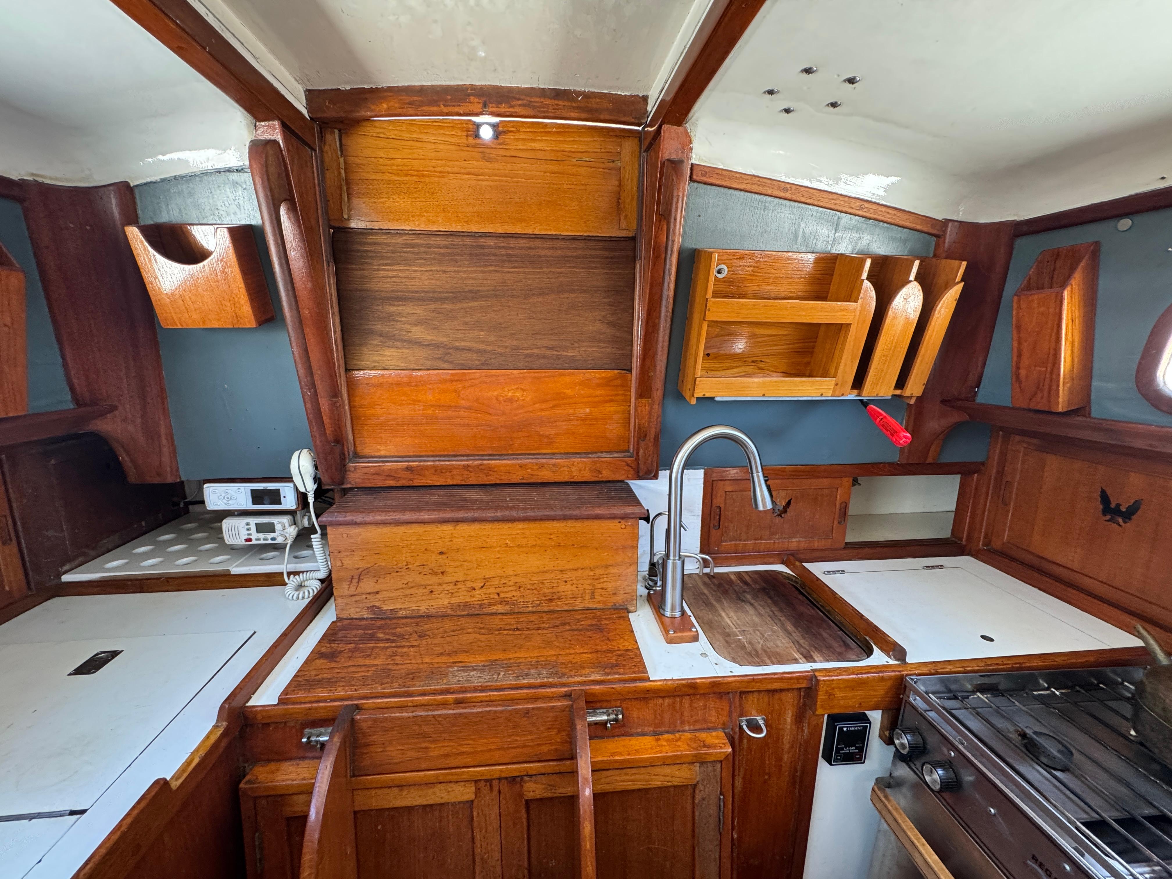 Interior of 1970 Cheoy Lee Luders 36 sailboat with wooden cabinetry and compact kitchen area.