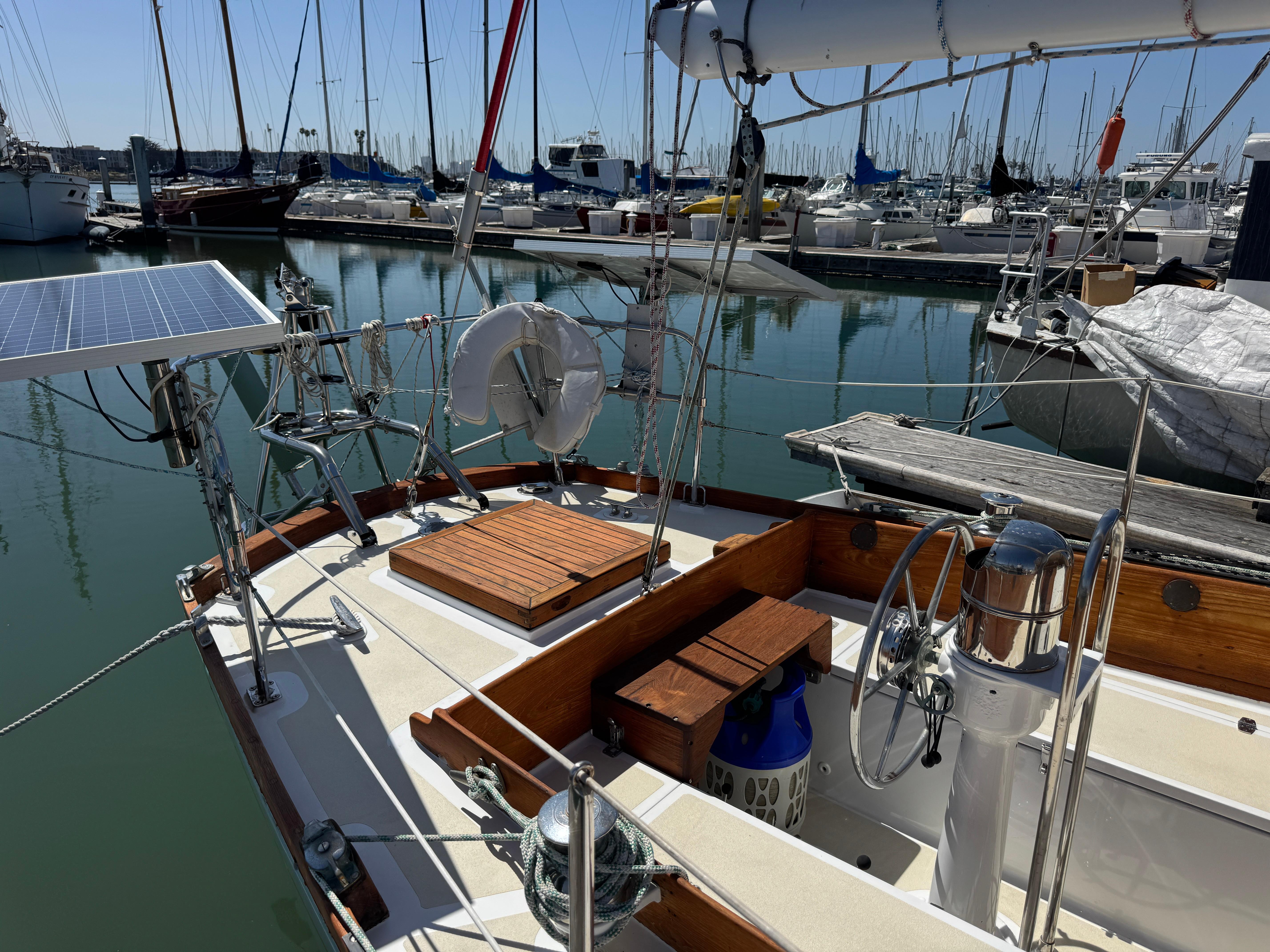 1970 Cheoy Lee Luders 36 sailboat docked in marina, featuring solar panel and wooden deck.