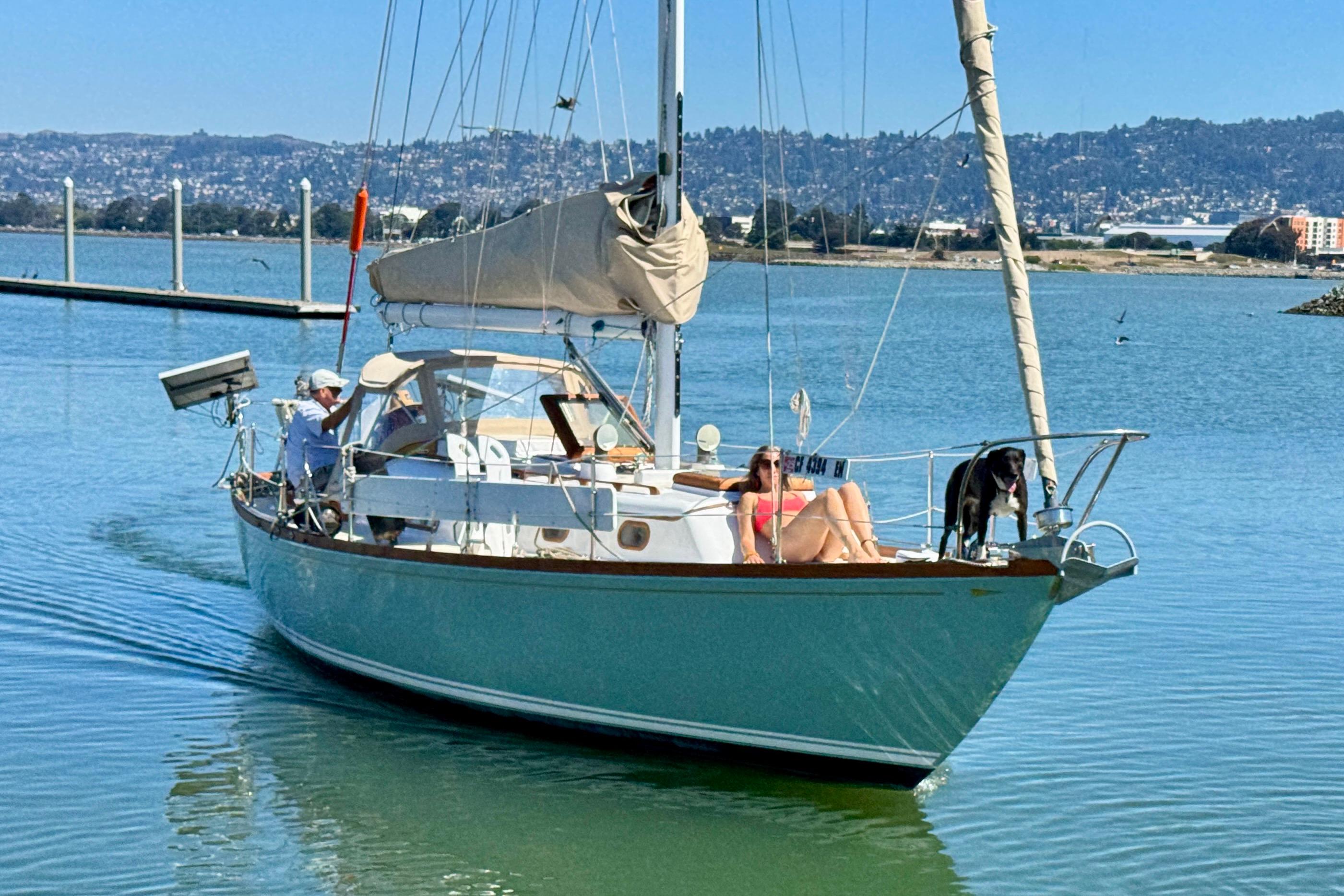 1970 Cheoy Lee Luders 36 sailboat cruising with passengers and a dog on a sunny day.