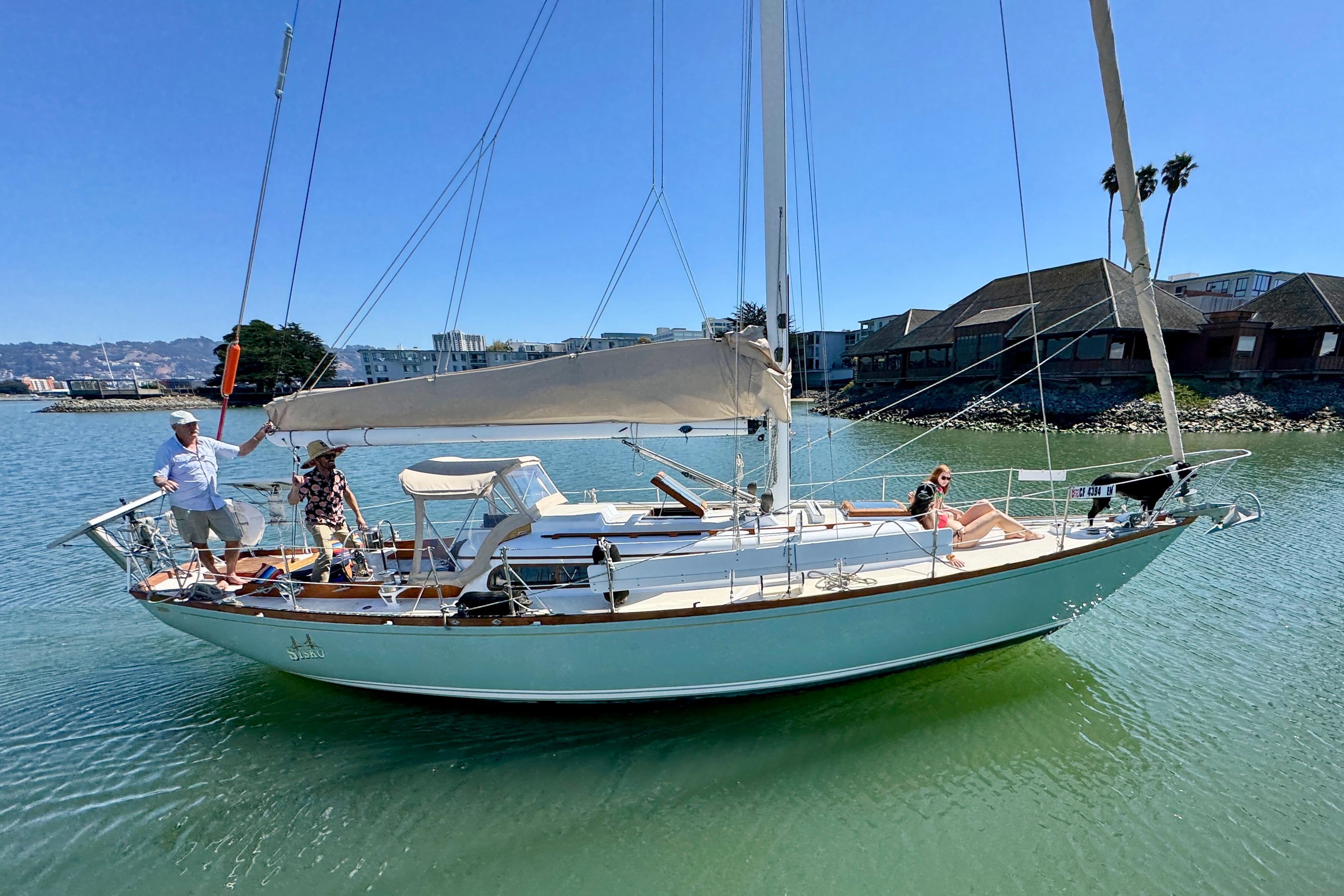 1970 Cheoy Lee Luders 36 sailboat on calm water with people enjoying a sunny day.
