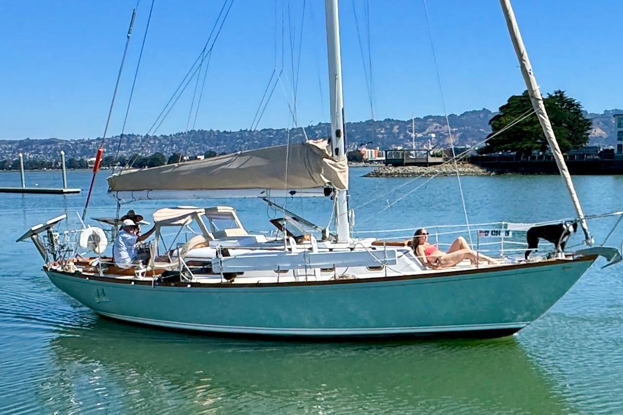 1970 Cheoy Lee Luders 36 sailboat on calm water, with people relaxing onboard.
