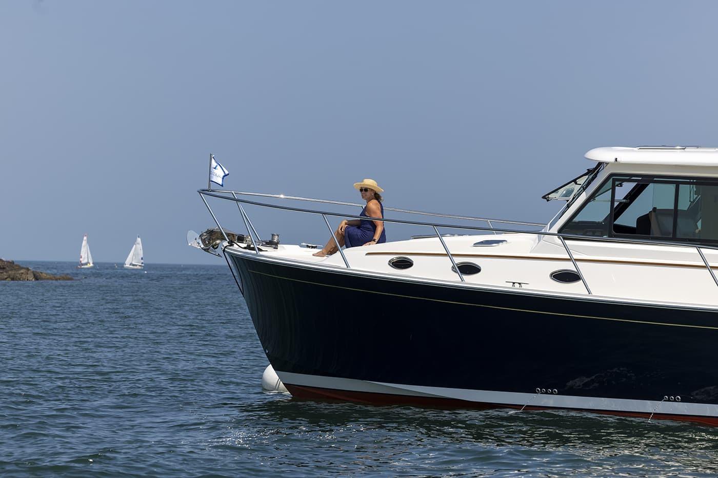 2026 Back Cove 412 yacht cruising with person relaxing on deck, sailboats in background.