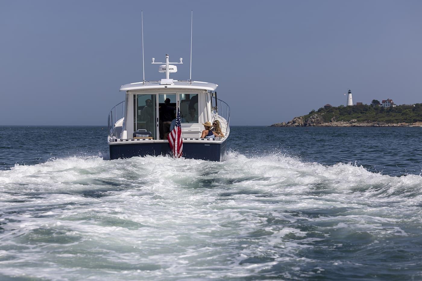 Back Cove 412 (2026) cruising near a lighthouse on a clear day.