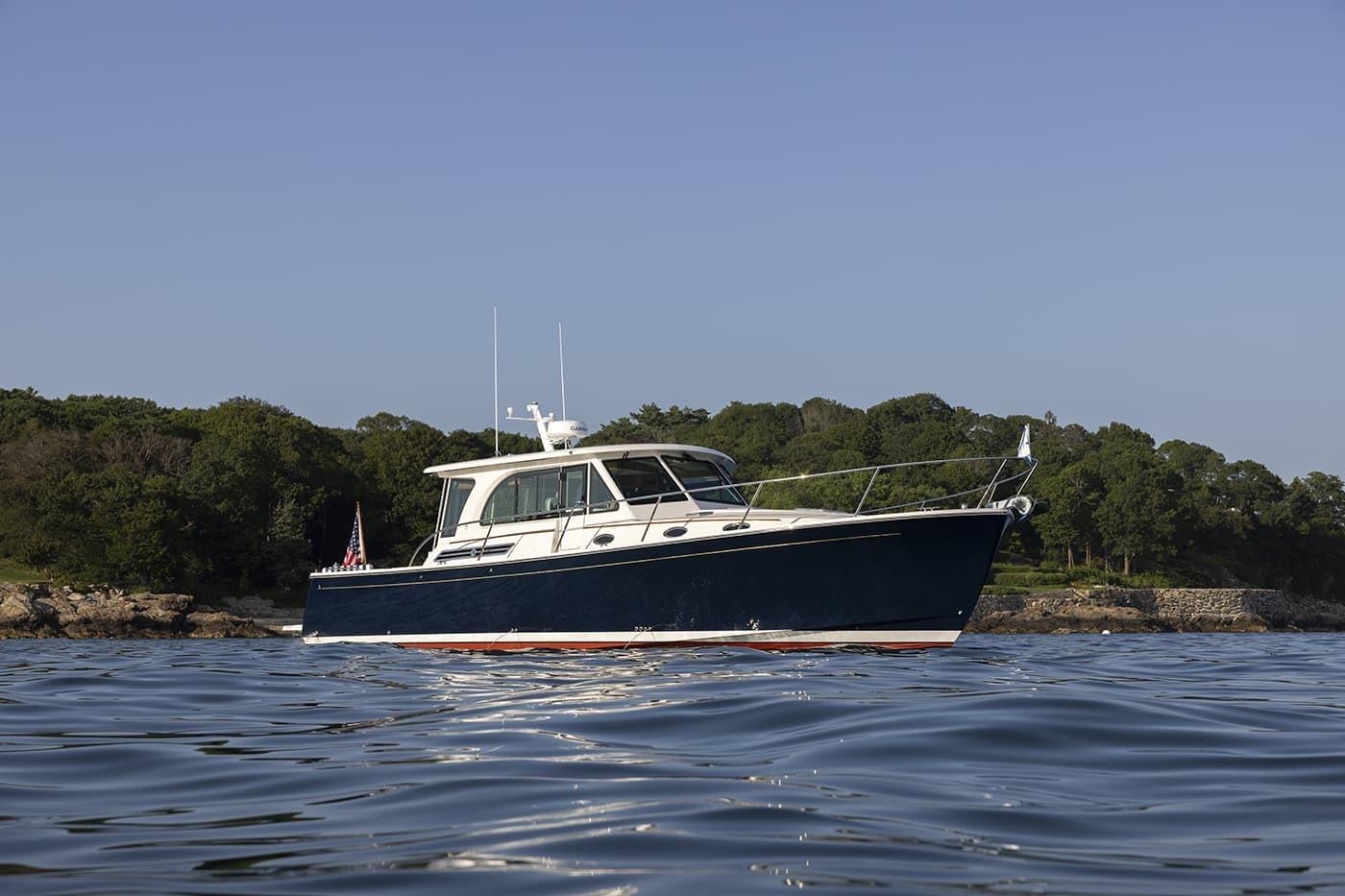 2026 Back Cove 412 yacht on calm water with scenic shoreline backdrop.