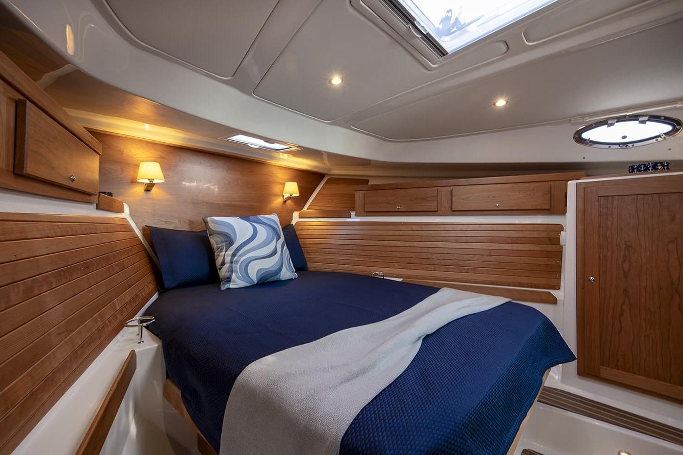 Luxurious cabin interior of 2026 Back Cove 412 yacht with wood paneling and cozy bedding.