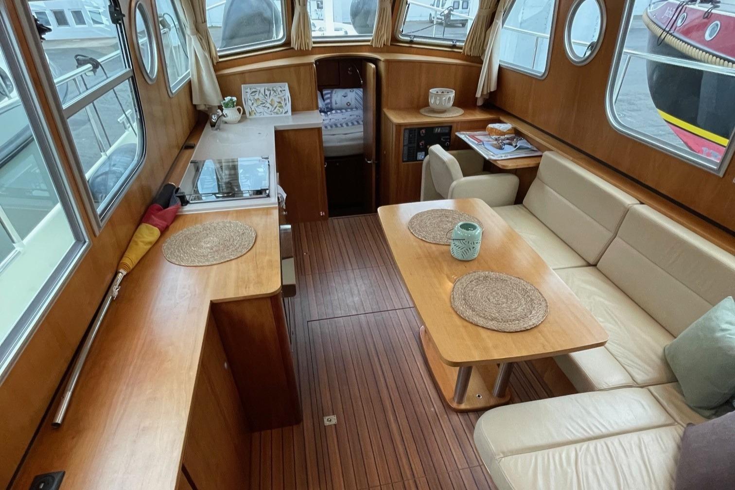 Interior of 2012 Linssen 36.9 boat with wooden furnishings and cozy seating area.