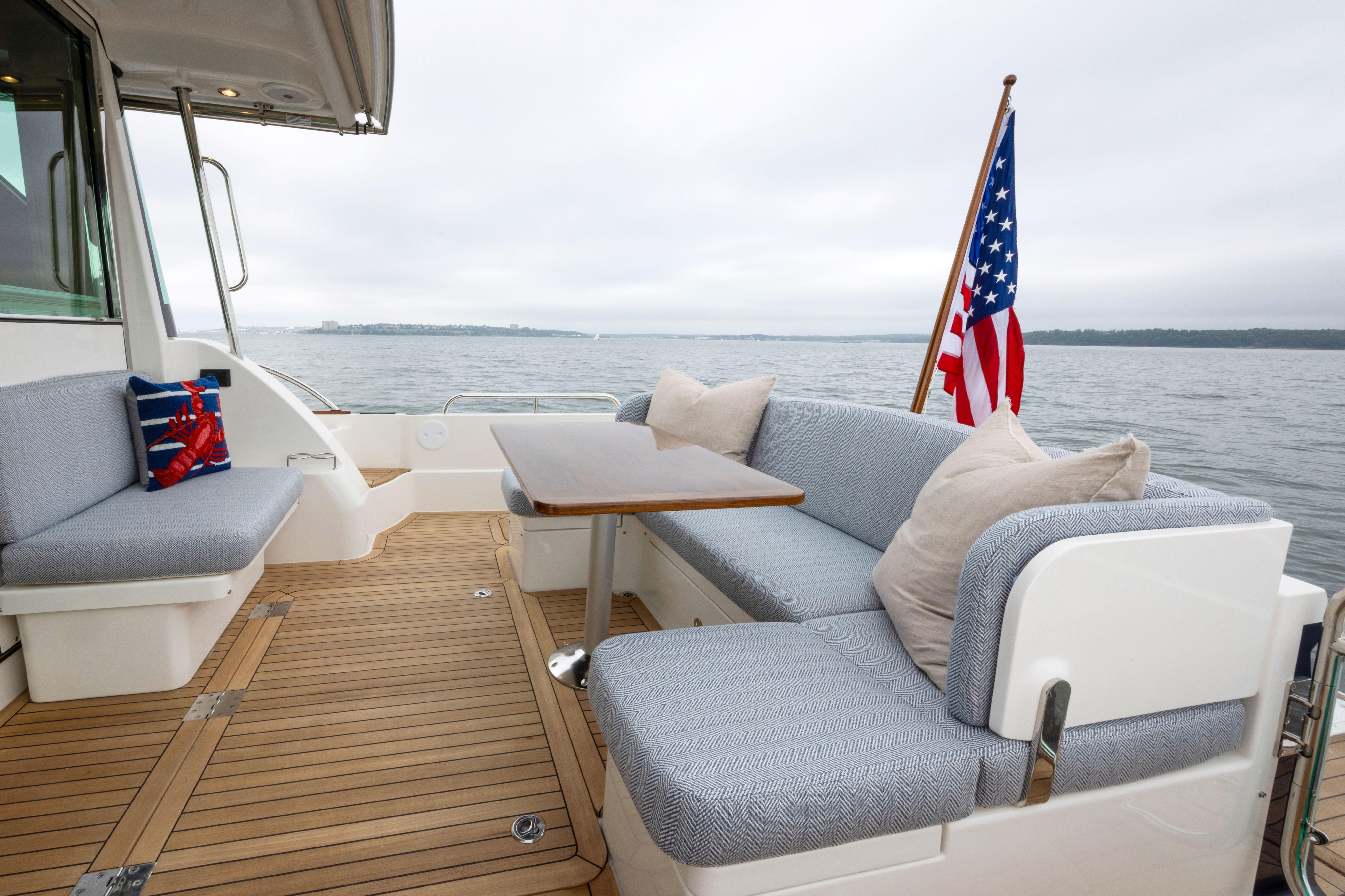 Elegant 2026 Sabre 45 Salon Express yacht deck with seating, table, and American flag.