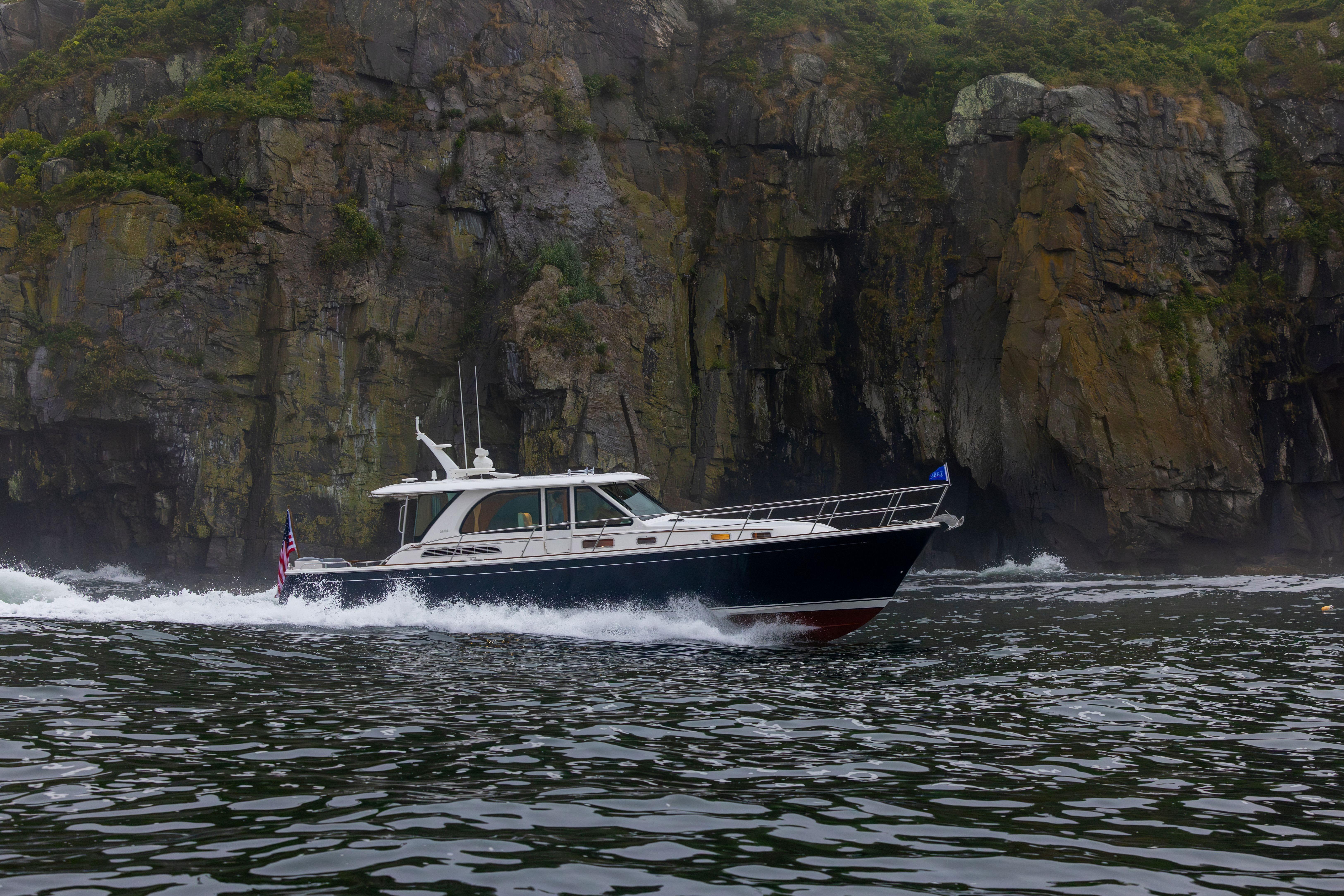 2026 Sabre 45 Salon Express cruising near rocky cliffs in scenic waters.