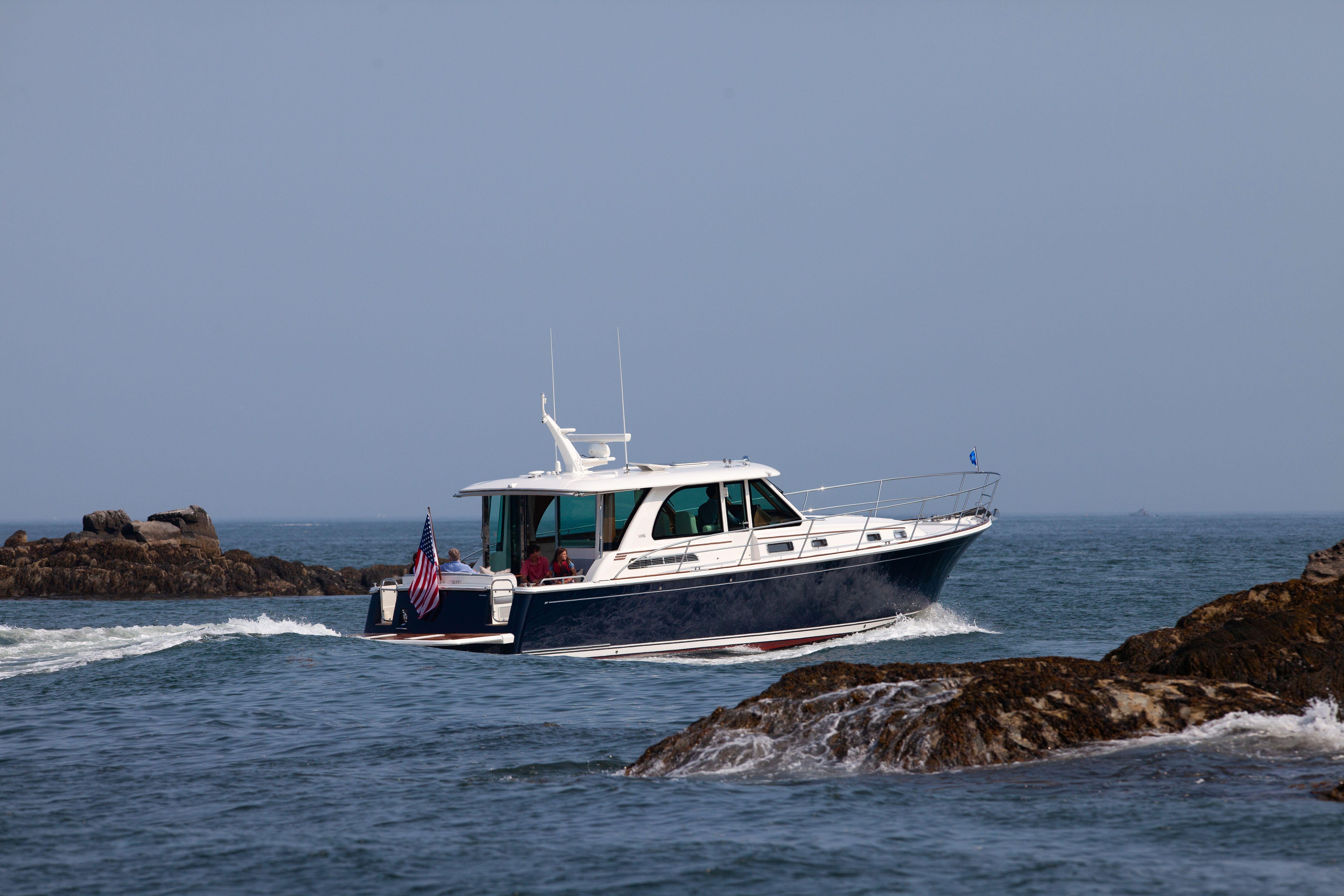 2026 Sabre 45 Salon Express cruising near rocky coastline.
