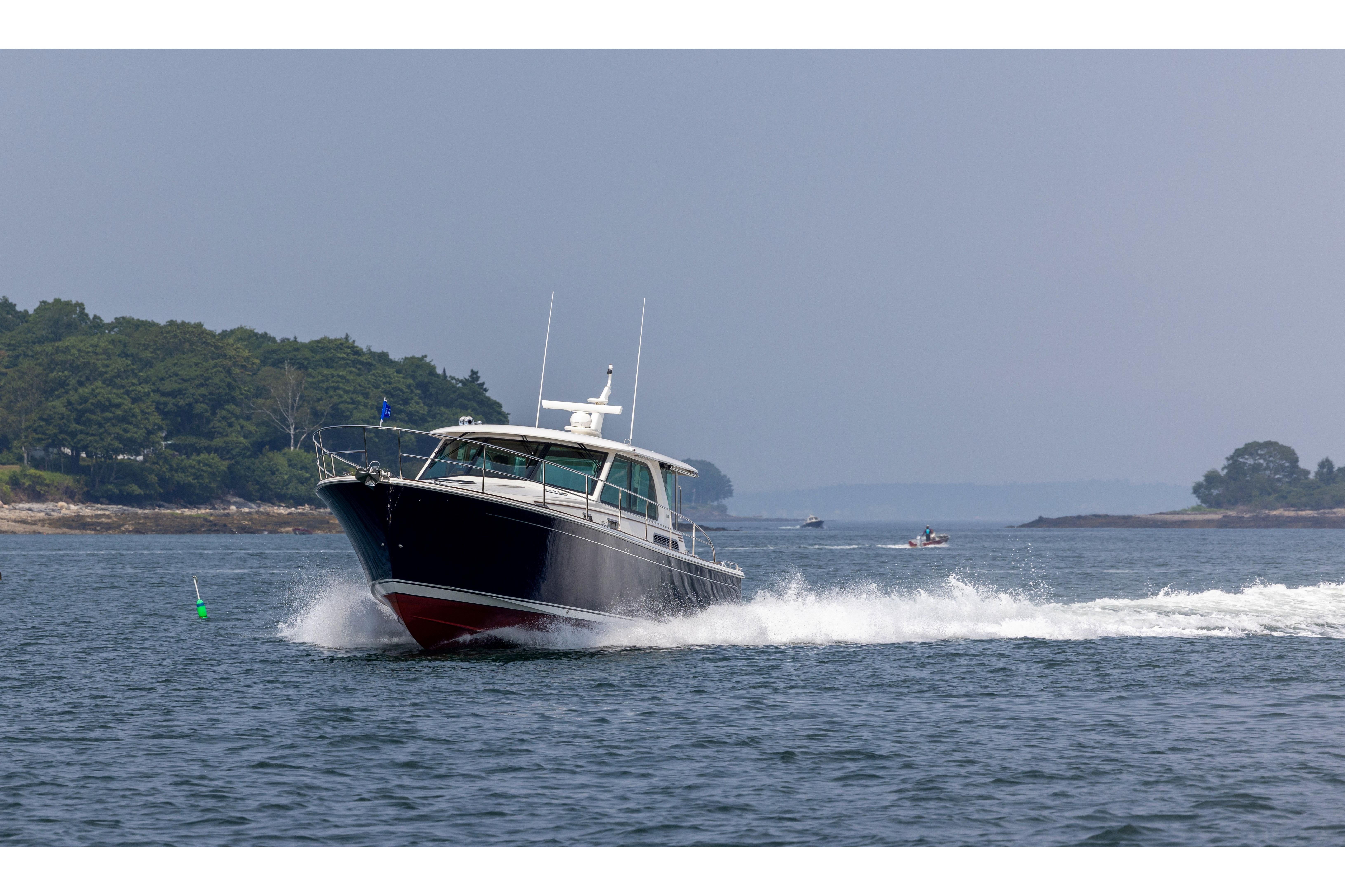 2026 Sabre 45 Salon Express cruising on open water near a lush, green shoreline.