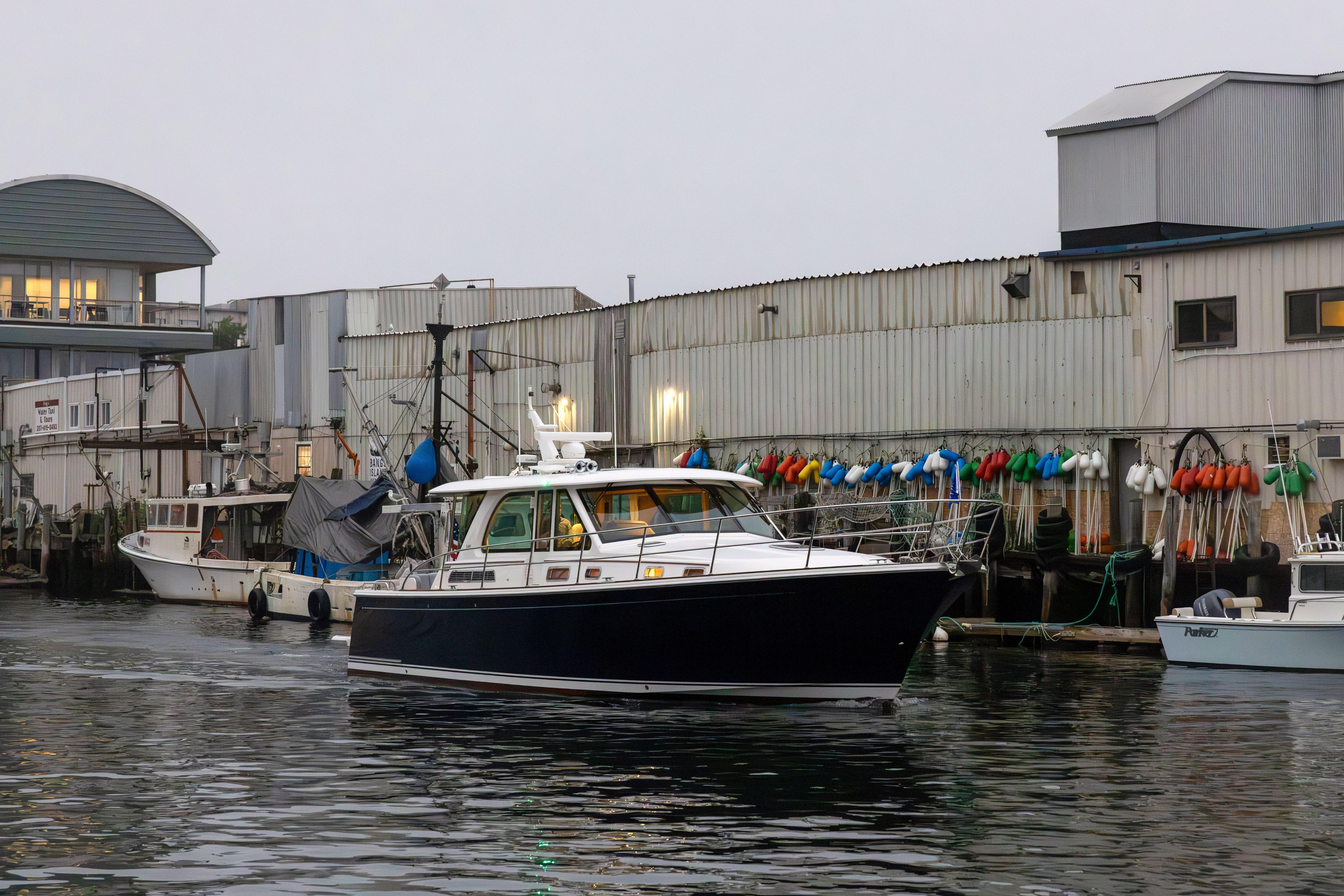 2026 Sabre 45 Salon Express yacht docked near industrial waterfront buildings.