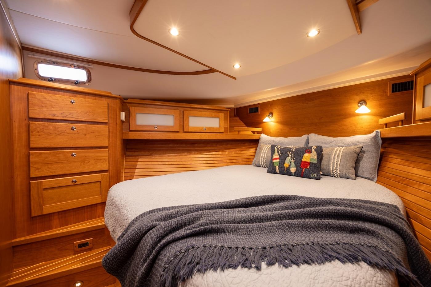 Luxurious cabin interior of 2027 Sabre 51 Salon Express yacht, featuring cozy bedding and wooden finishes.