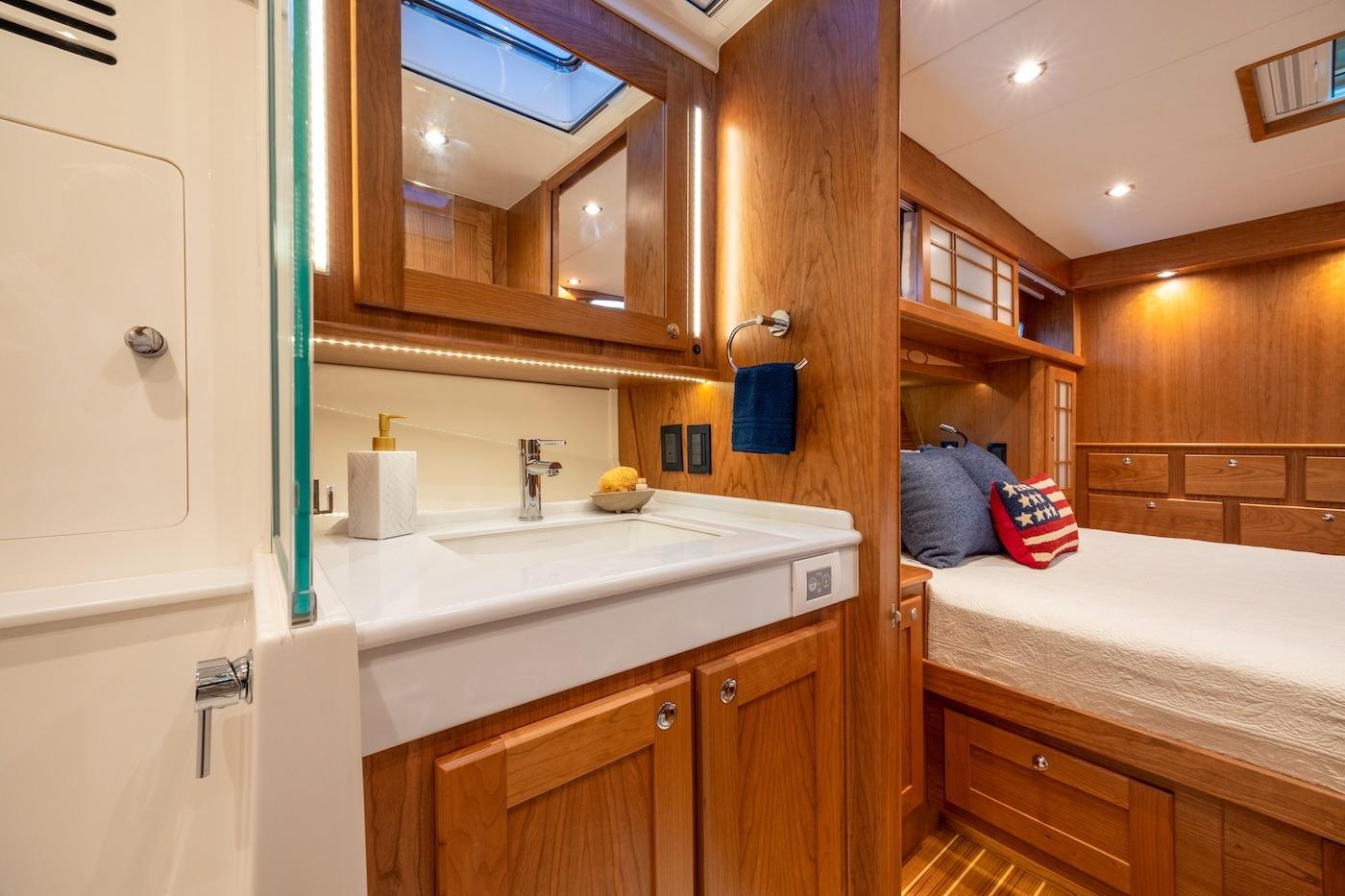 Luxurious interior of 2027 Sabre 51 Salon Express yacht with wooden cabinetry and cozy bedroom.