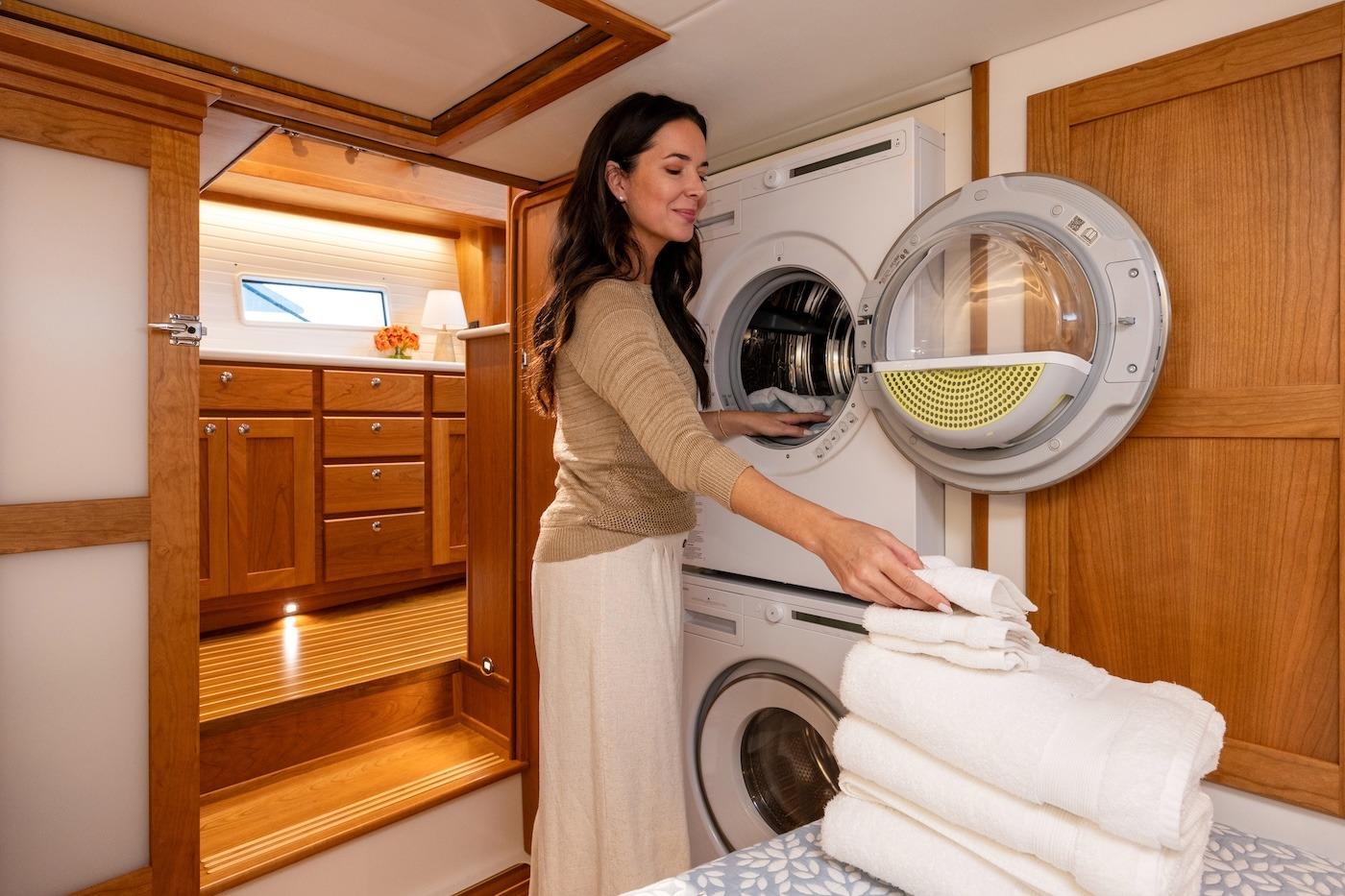 Woman doing laundry in 2027 Sabre 51 Salon Express yacht interior.