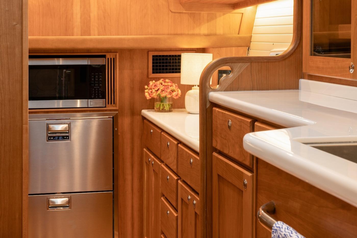 2027 Sabre 51 Salon Express yacht kitchen with wood cabinetry, stainless appliances, and elegant decor.