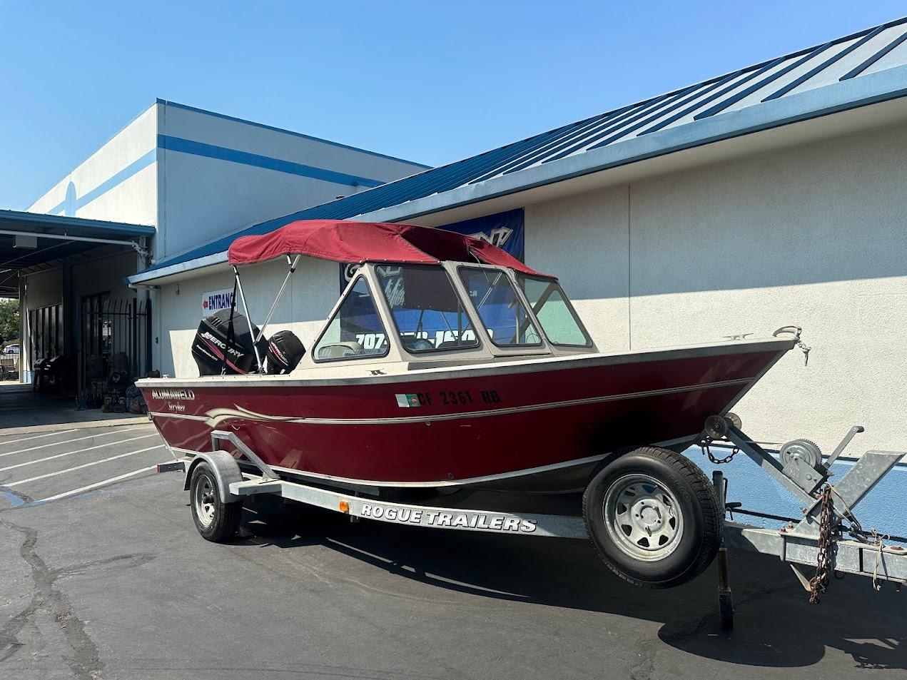 2003 Alumaweld Stryker boat on Rogue trailer, parked outside a building.