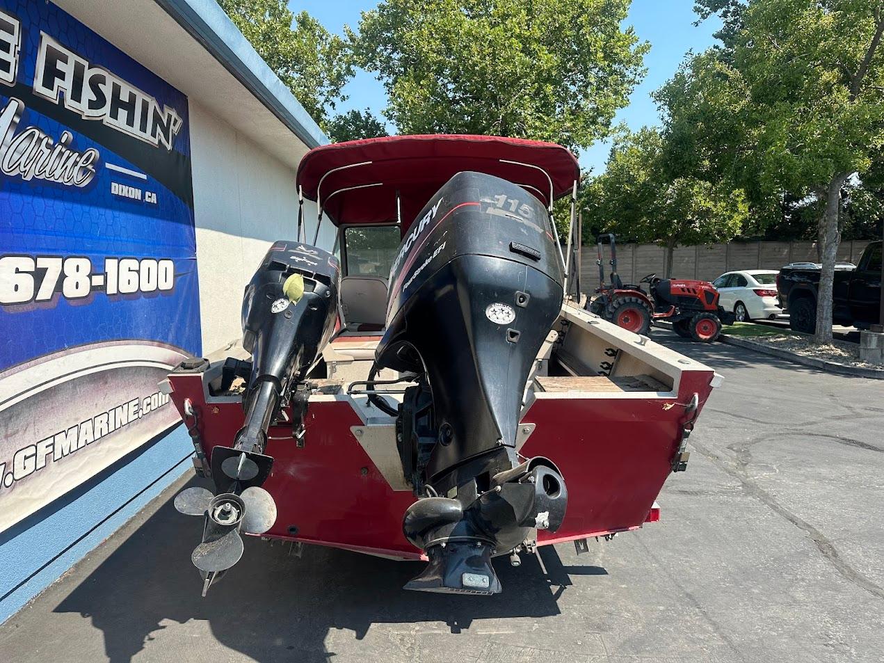 2003 Alumaweld Stryker boat with dual outboard motors, parked near a marine shop.