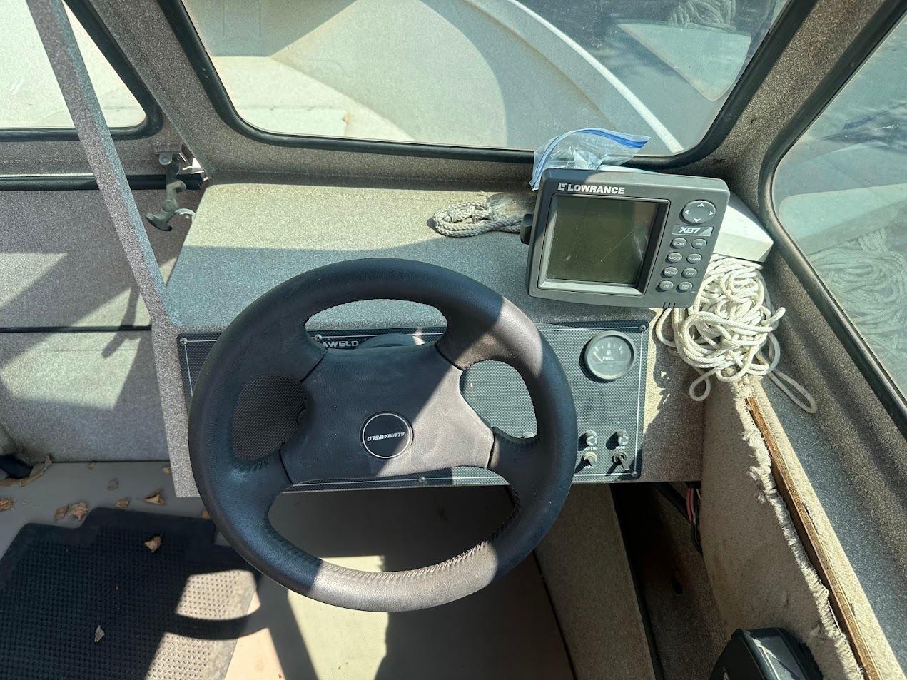 2003 Alumaweld Stryker boat dashboard with steering wheel and Lowrance X67 fish finder.