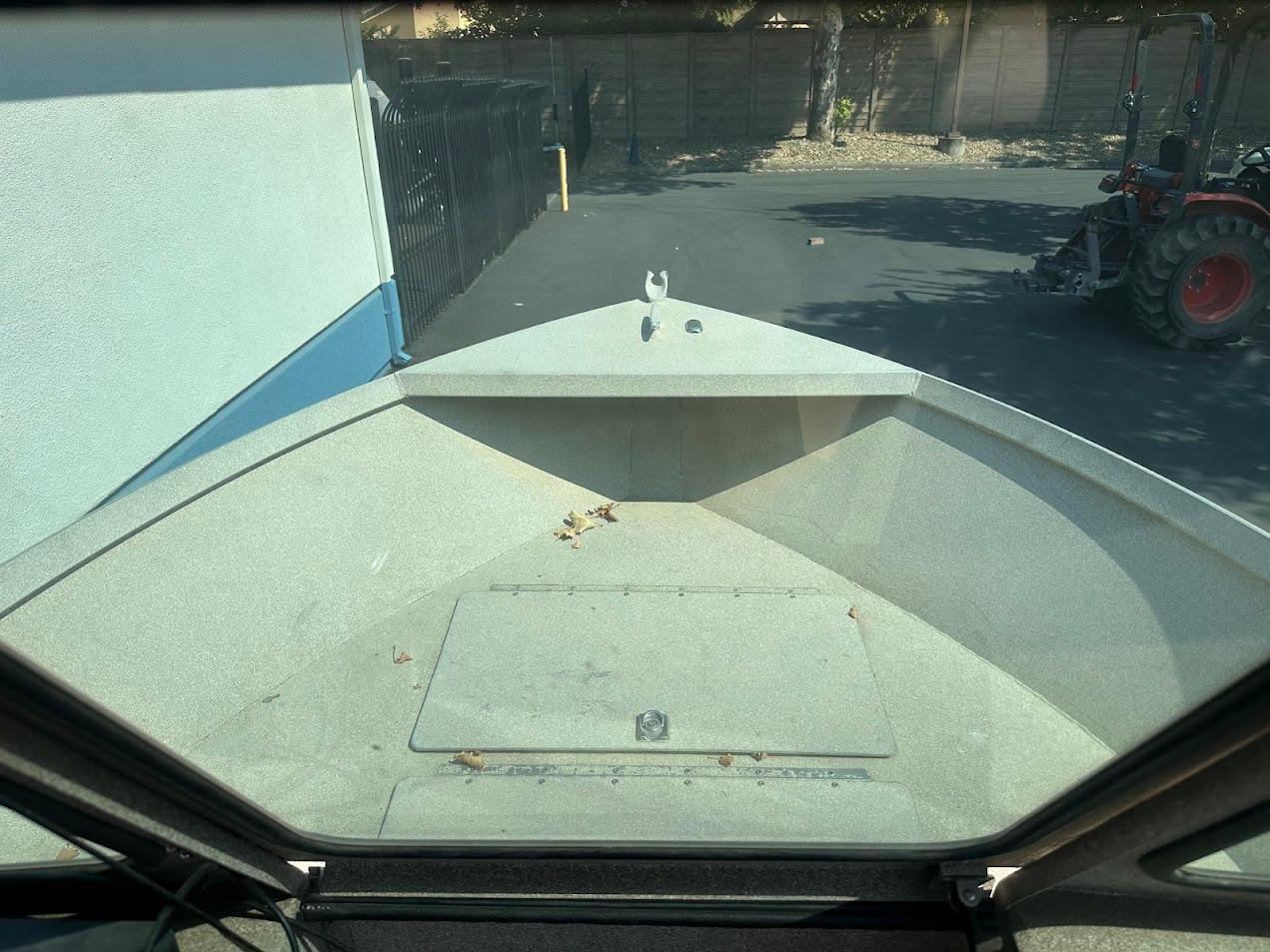2003 Alumaweld Stryker boat interior view, parked near a building and tractor.